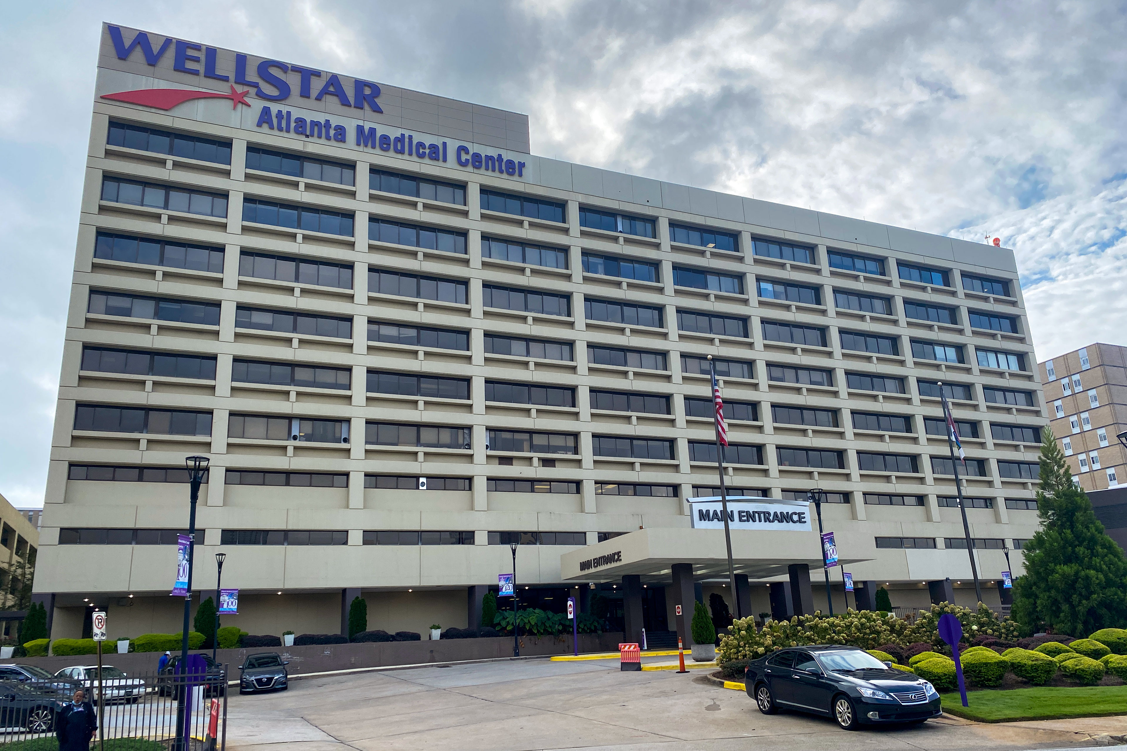 A hospital building about eight stories high with a "Main Entrance" sign in the middle of the ground floor.