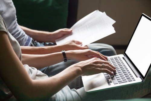 Close up of couple searching online information about legal document details with laptop, family studying important contract terms and conditions typing filling internet application form on website