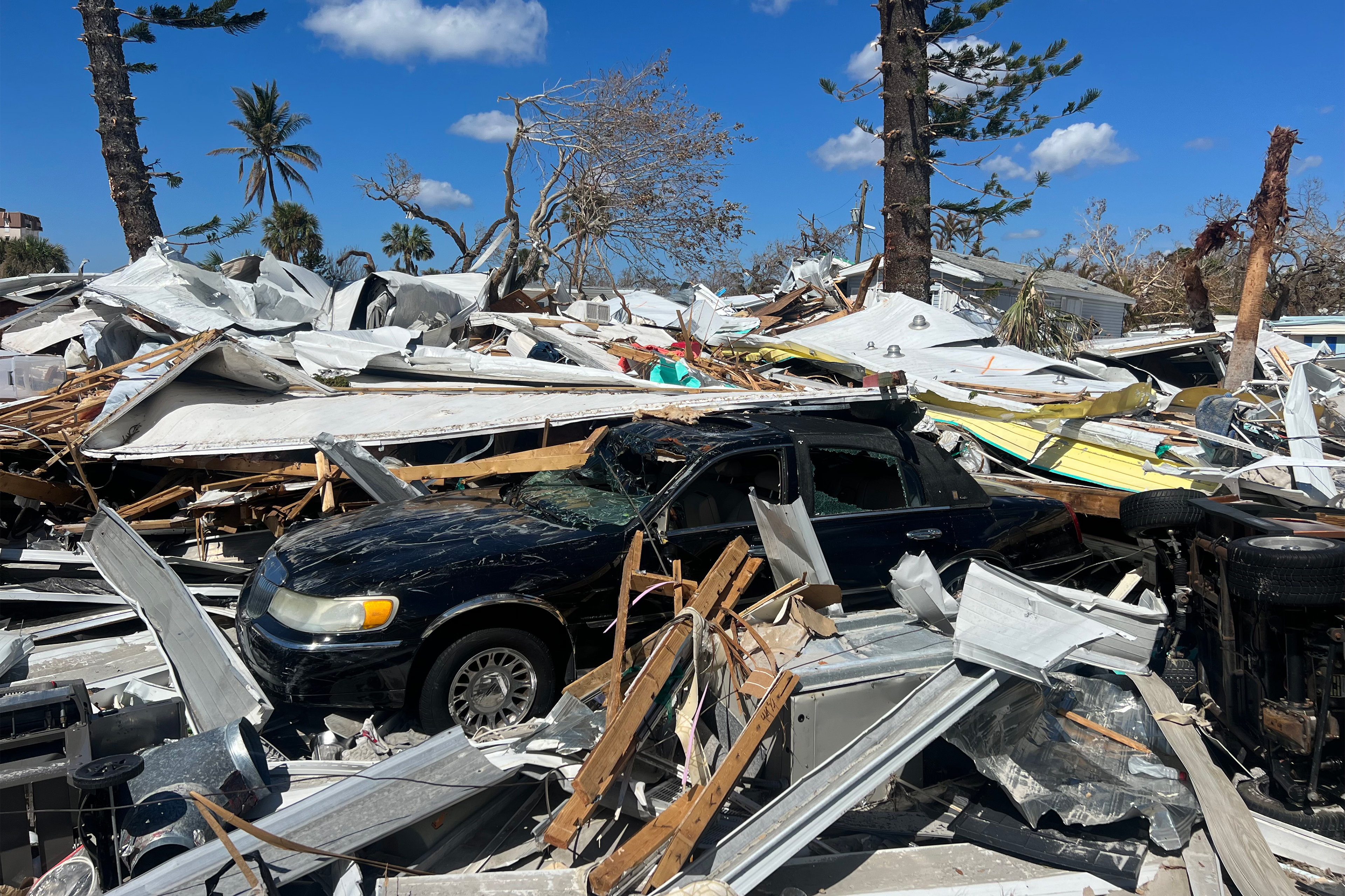 A photo shows a crushed car and debris, the aftermath of Hurricane Ian in Florida.