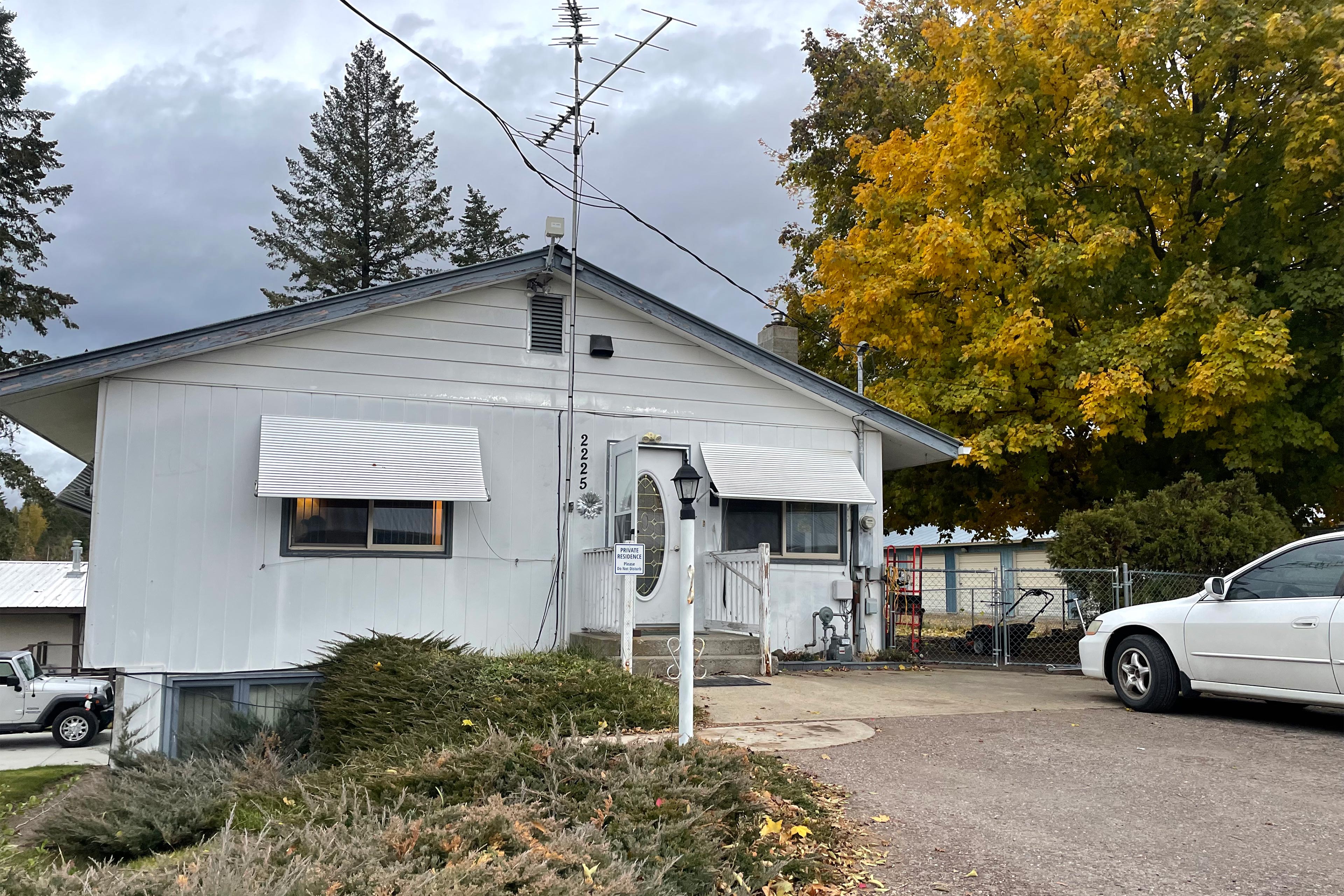 A photo shows the outside of a white rental home. A white car is parked in the driveway.