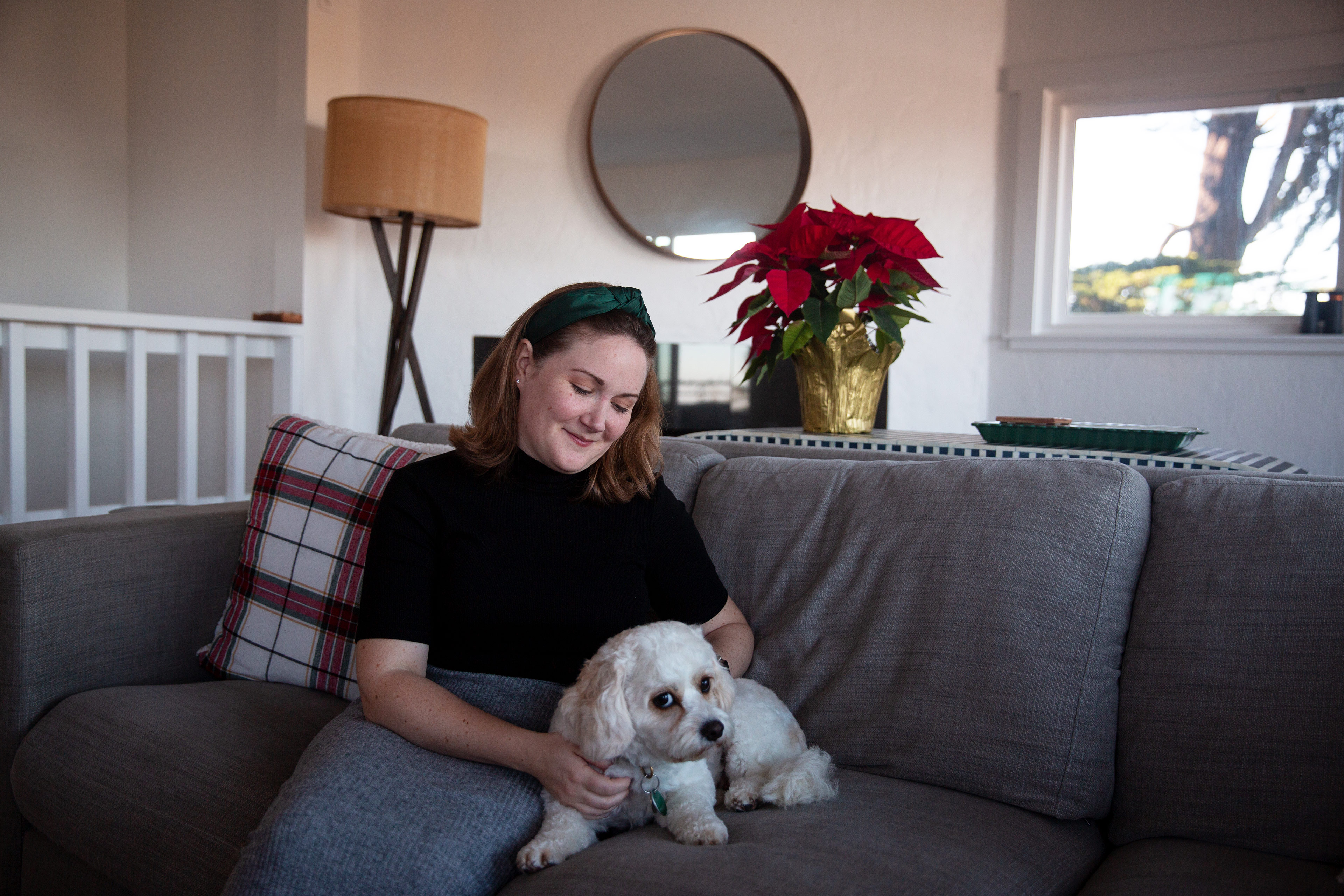 A photo shows Grace E. Elliott sitting on a couch at home, petting her dog.