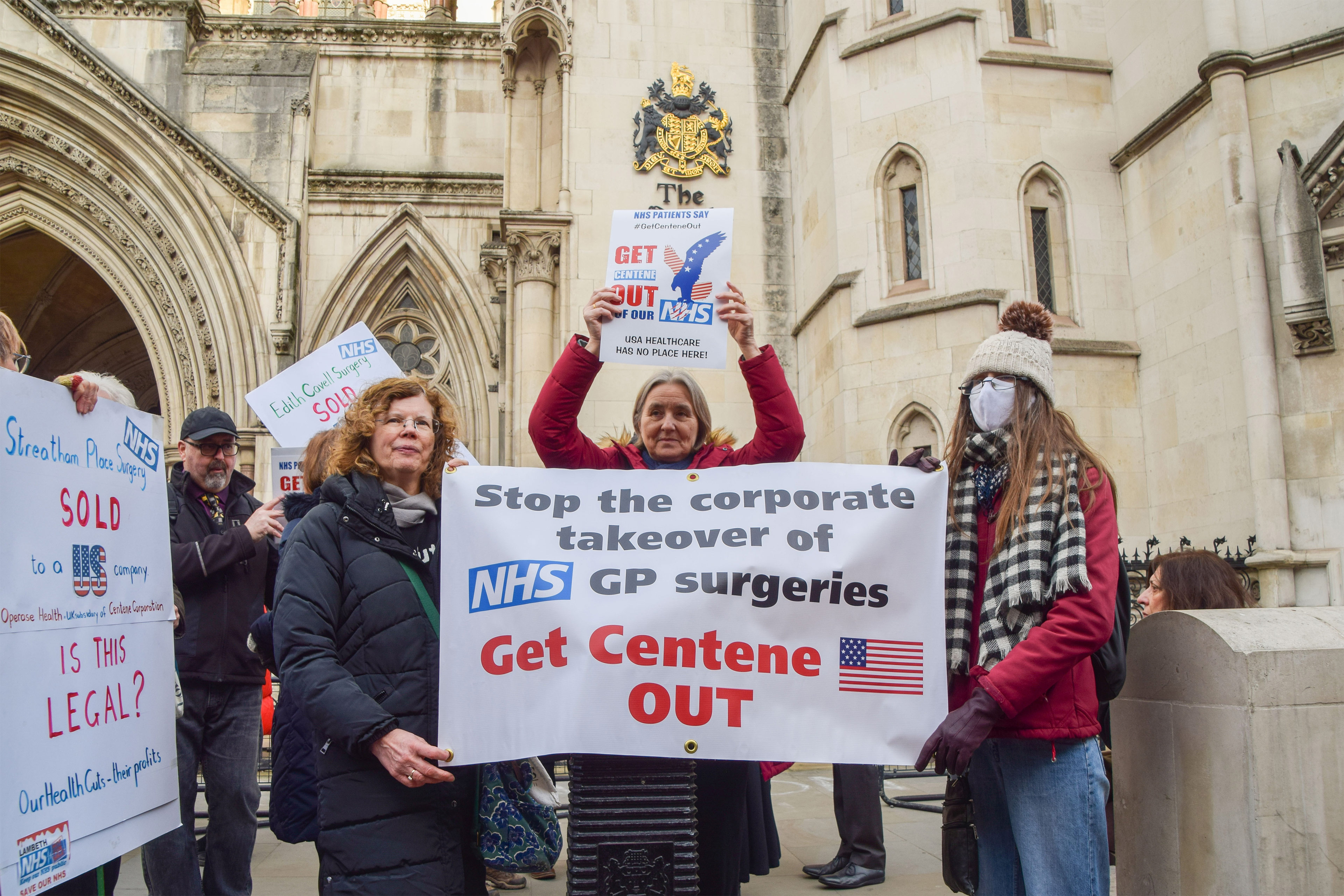 A photo shows two demonstrators holding a banner that reads, "Stop the corporate takeover of NHS GP surgeries. Get Centene out."