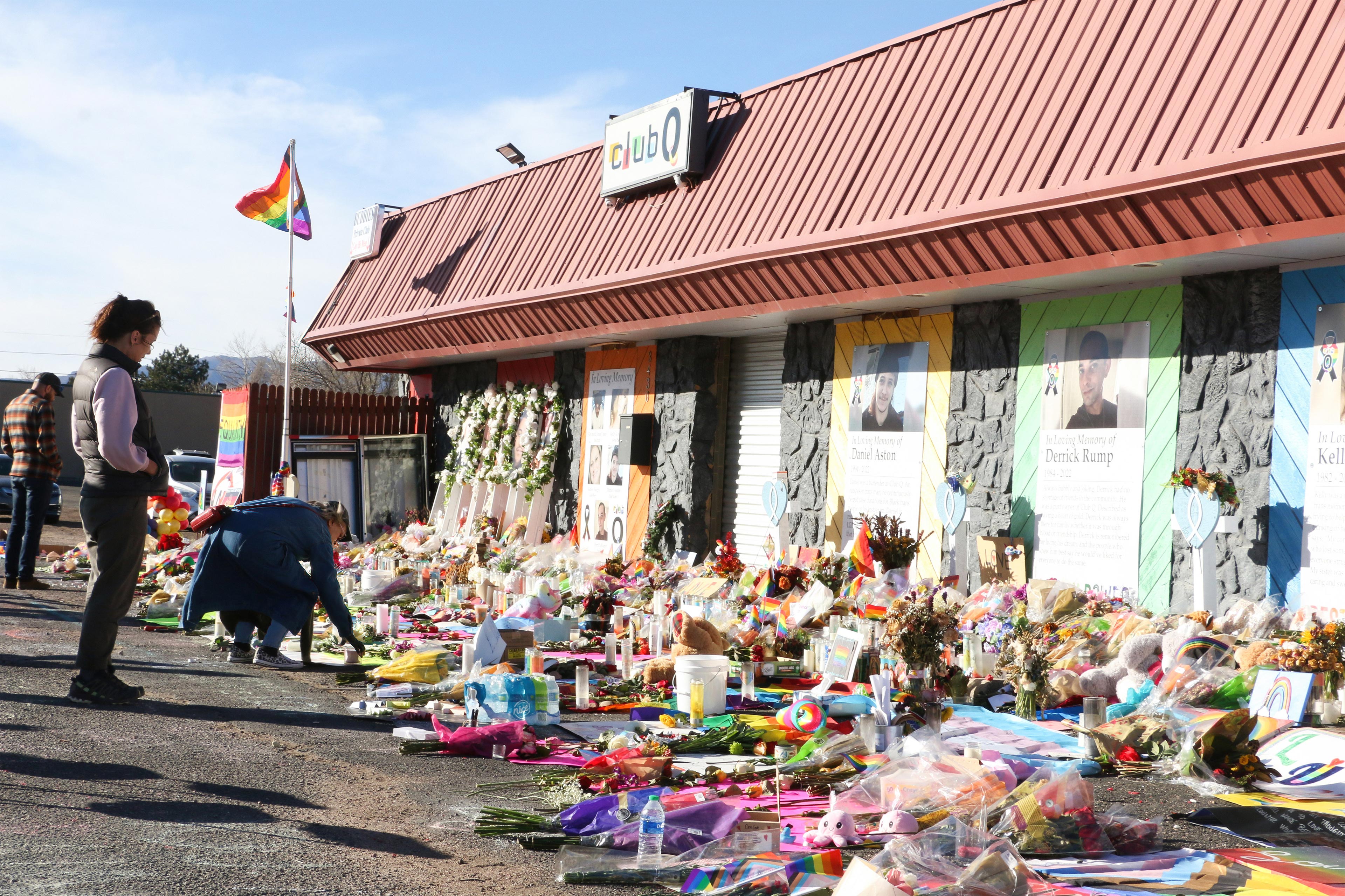 A photo shows bouquets of flowers, candles and stuffed animals displayed in front of the Club Q nightclub.