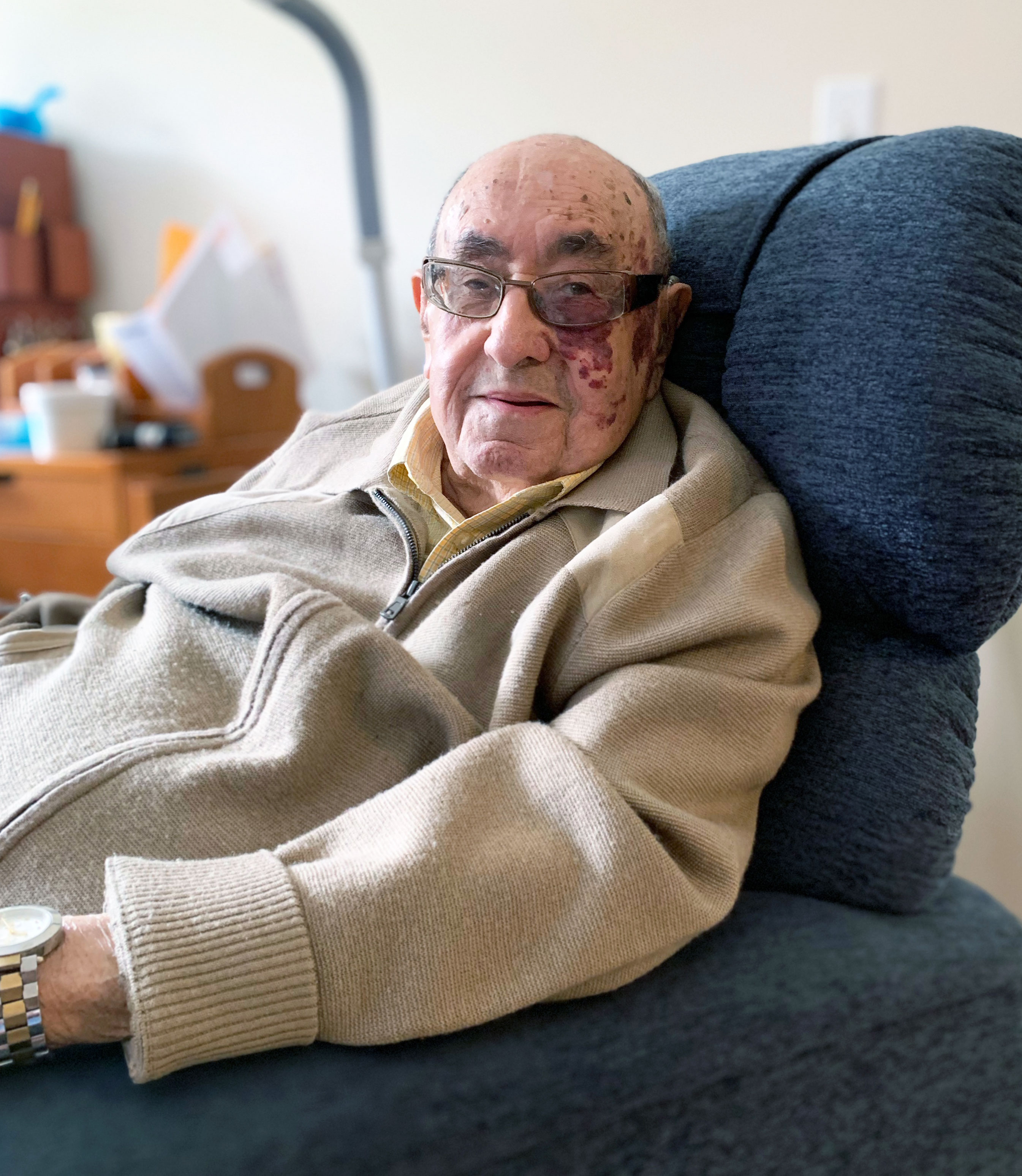 A photo shows Melvin Zax sitting at home.