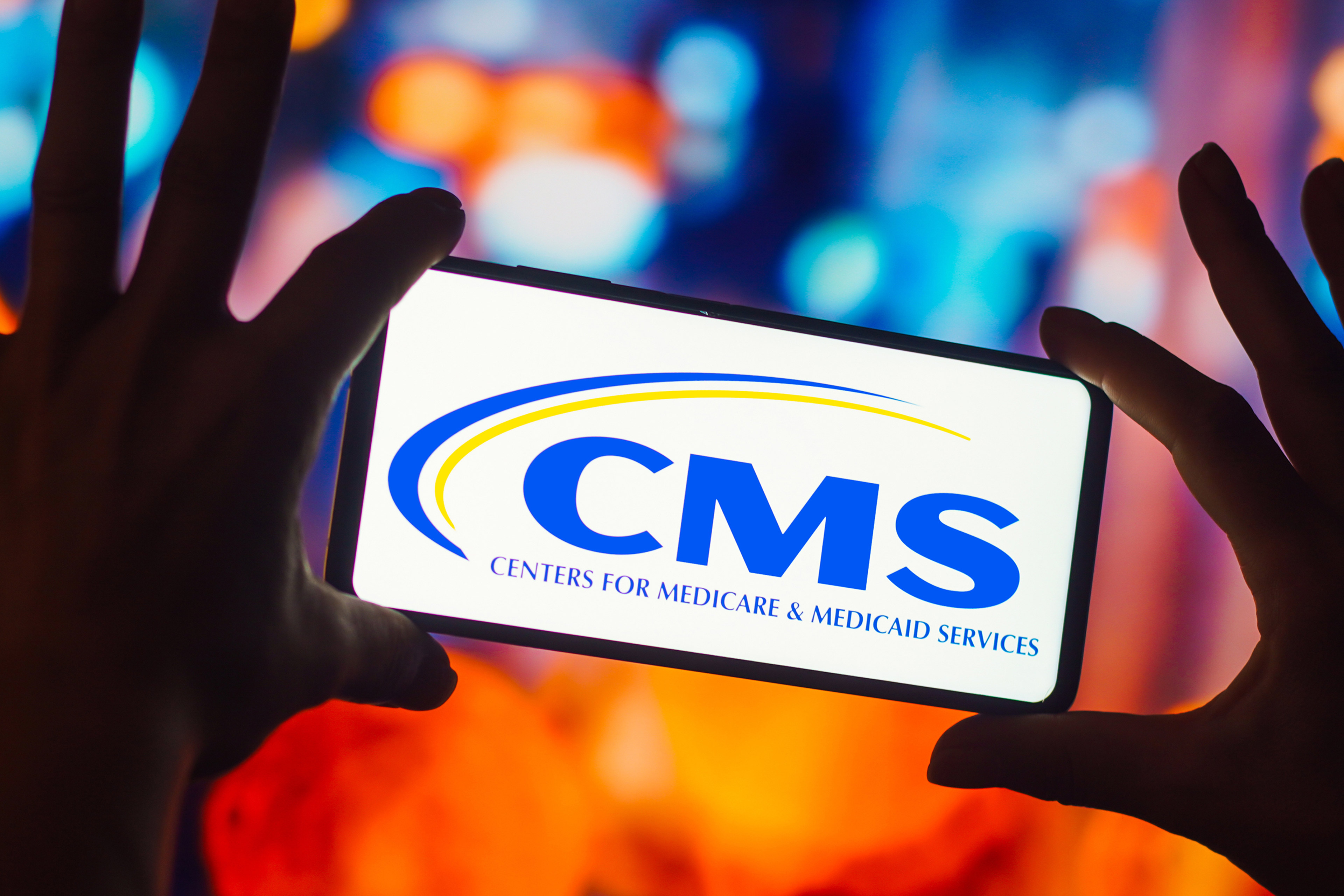 A photo illustration shows a phone showing an image of the Centers for Medicare and Medicaid Services logo.