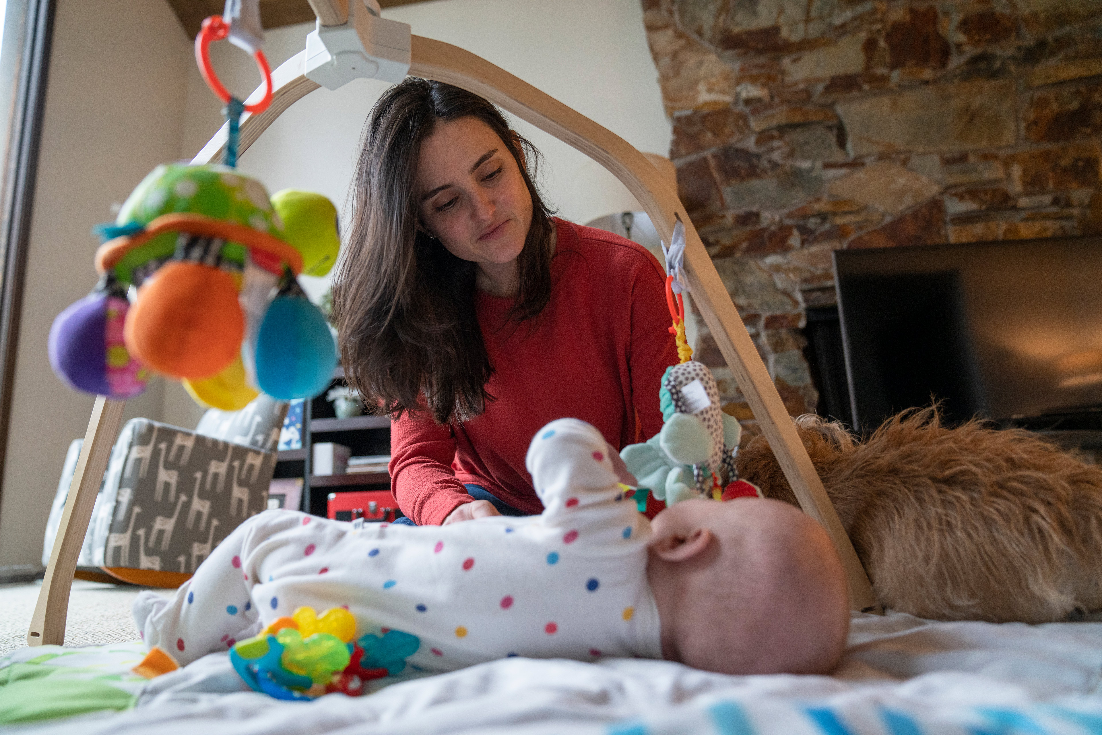 A photo shows a woman taking care of an infant baby lying on a padded floor mat.