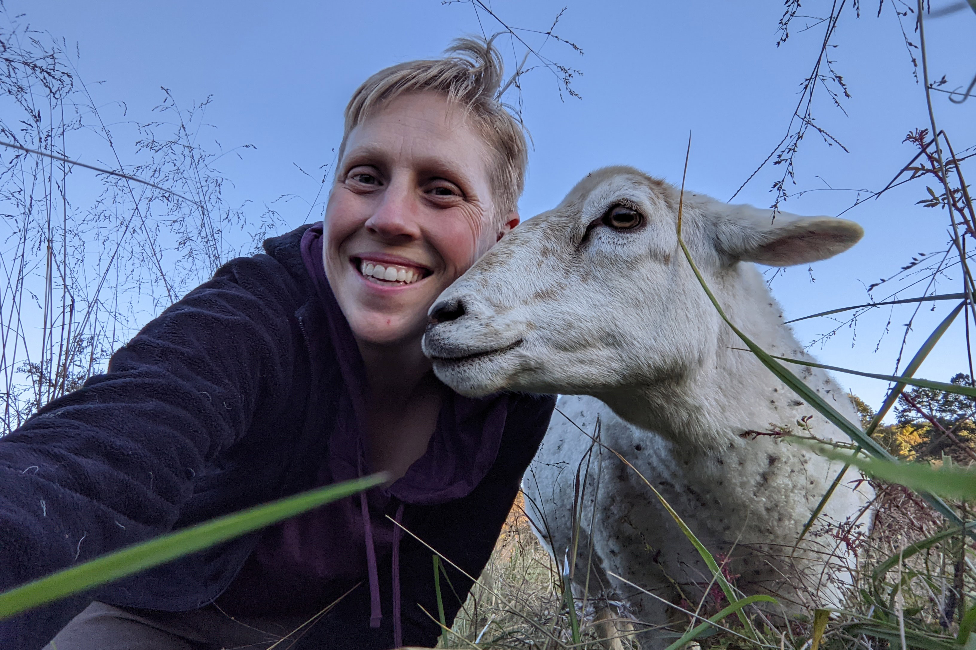A photo of A.C. Shilton posing with a sheep outside.