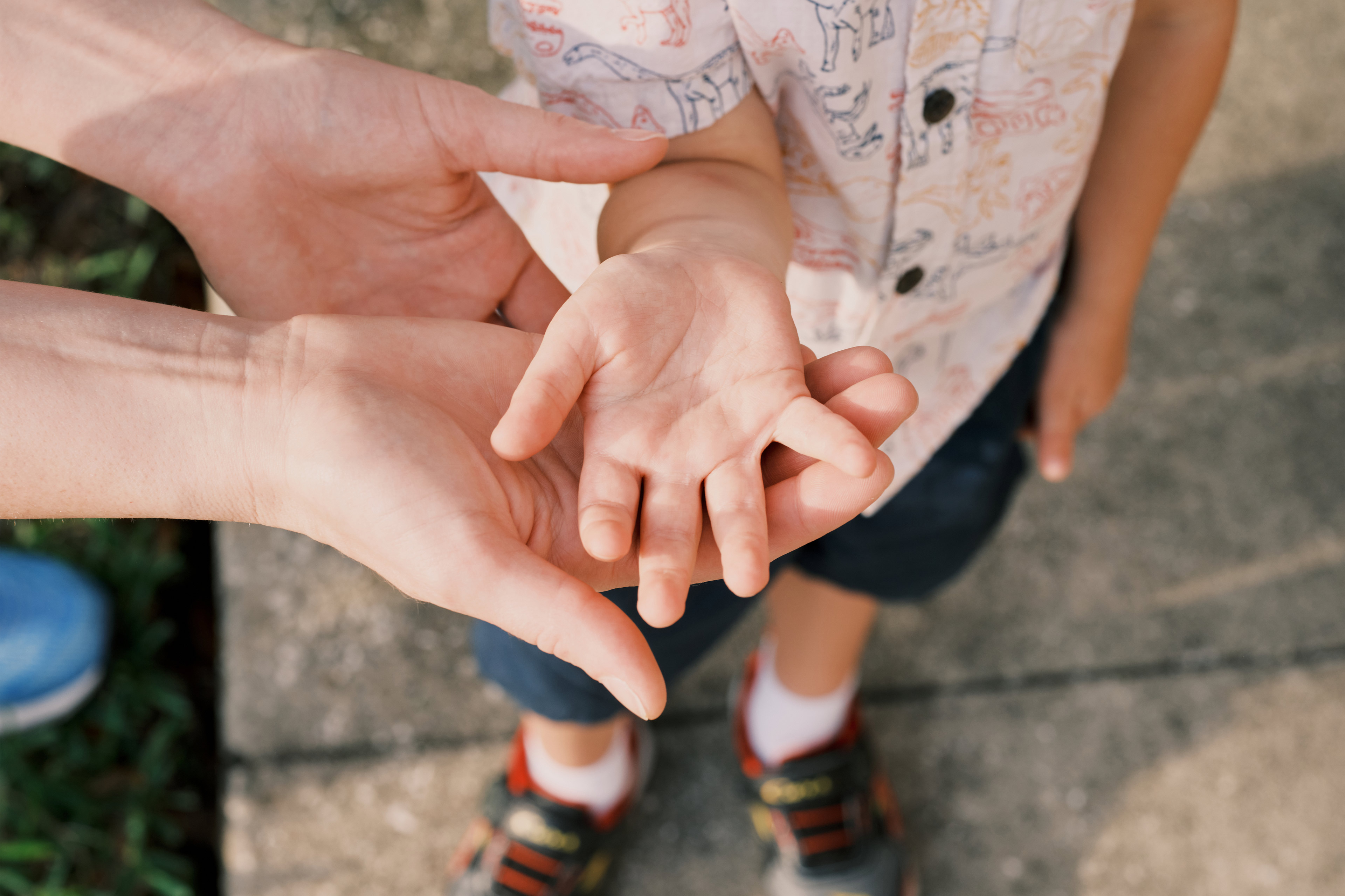 A photo of a mother holding up her young son's right hand.