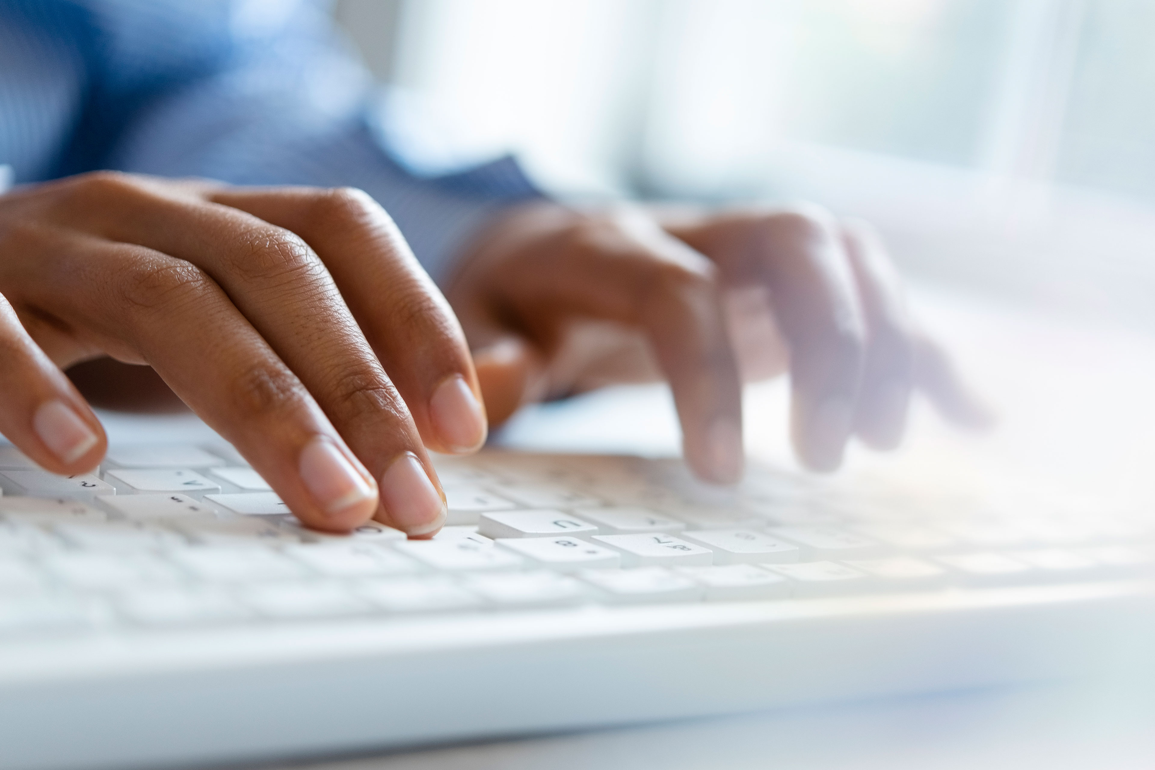 A close-up image shows two hands typing on a keyboard.