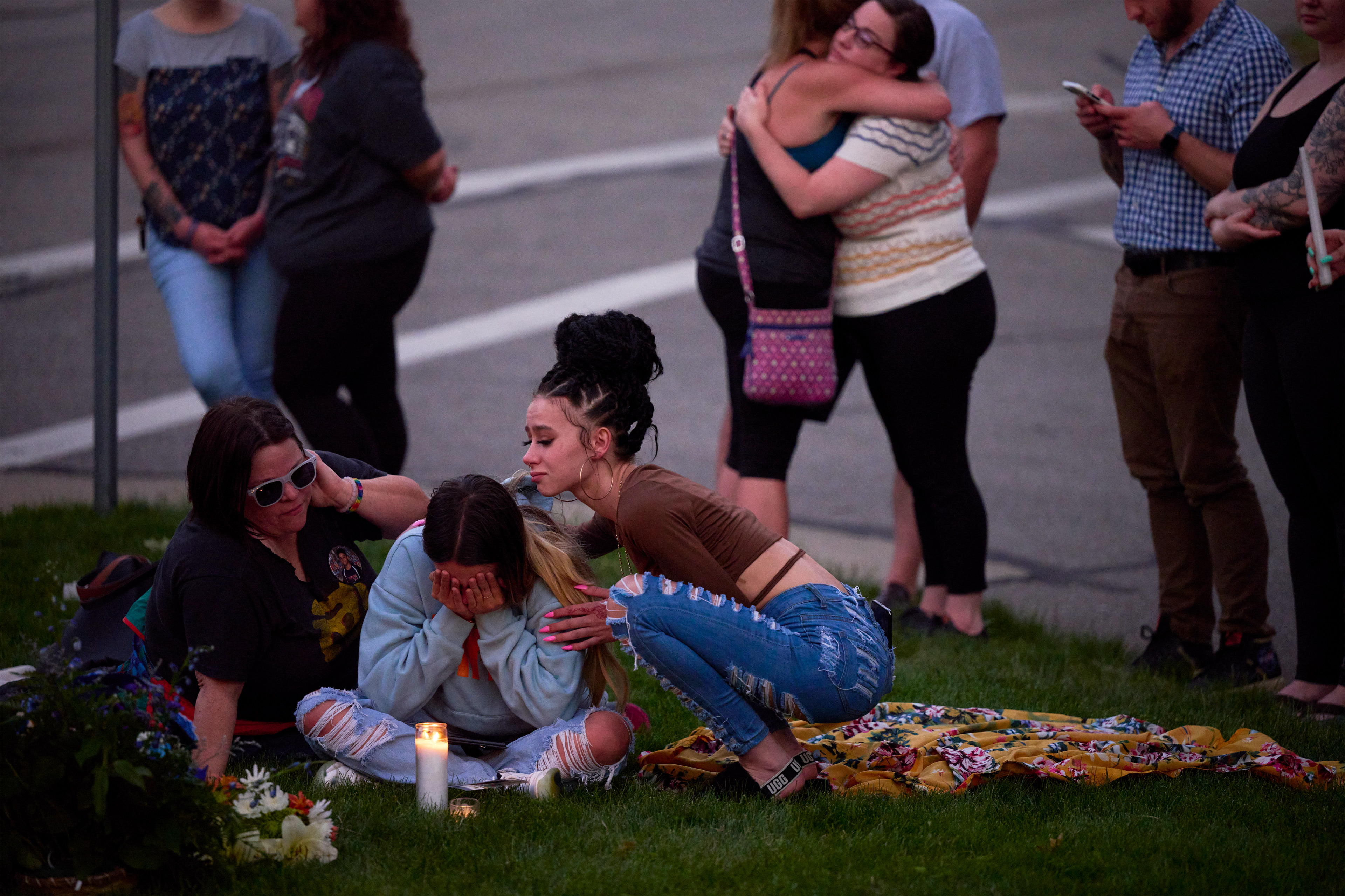 A photo shows a teenage girl crying while being comforted by two women ata