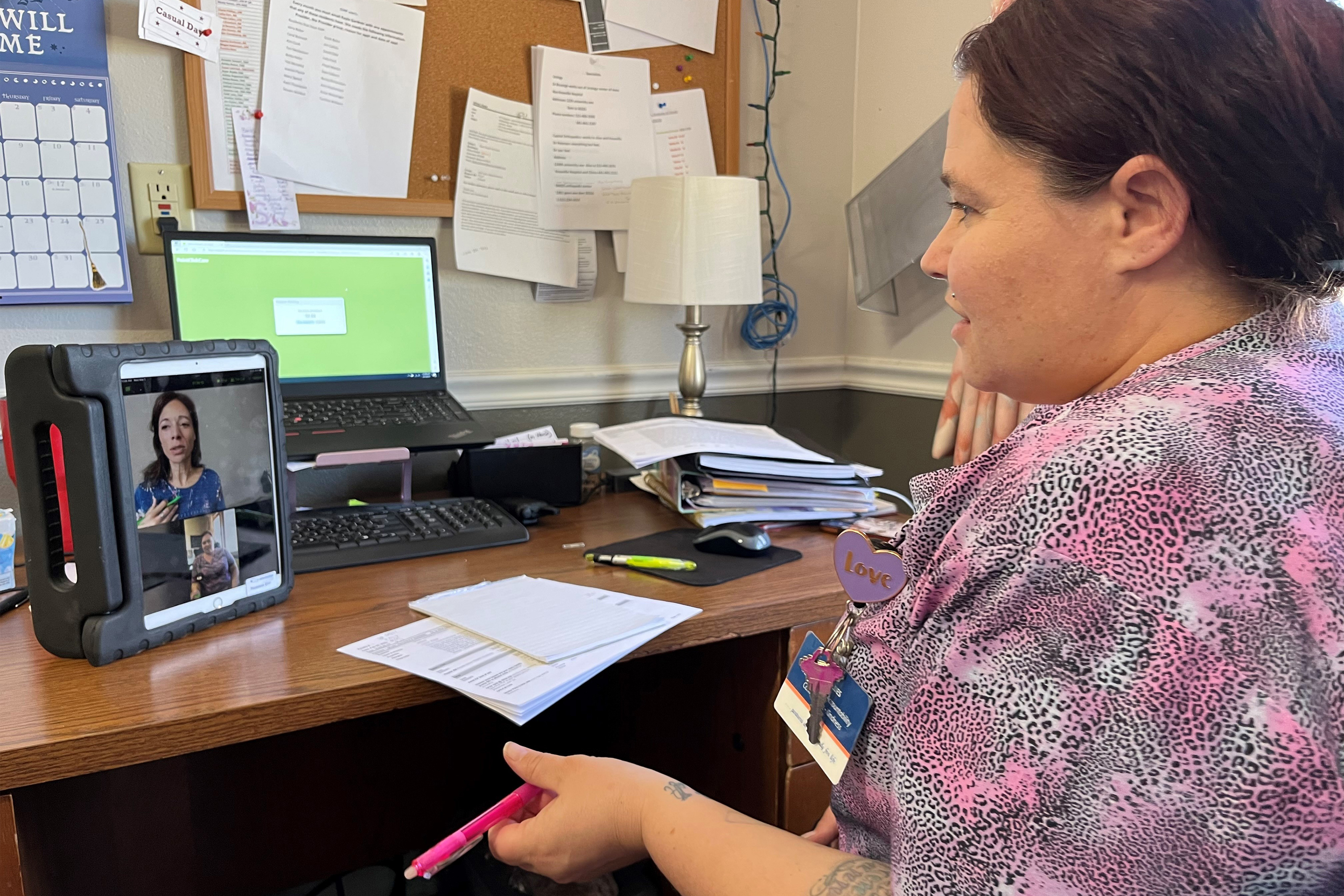 A photo of a nursing home worker speaking to a mental health worker via video call.
