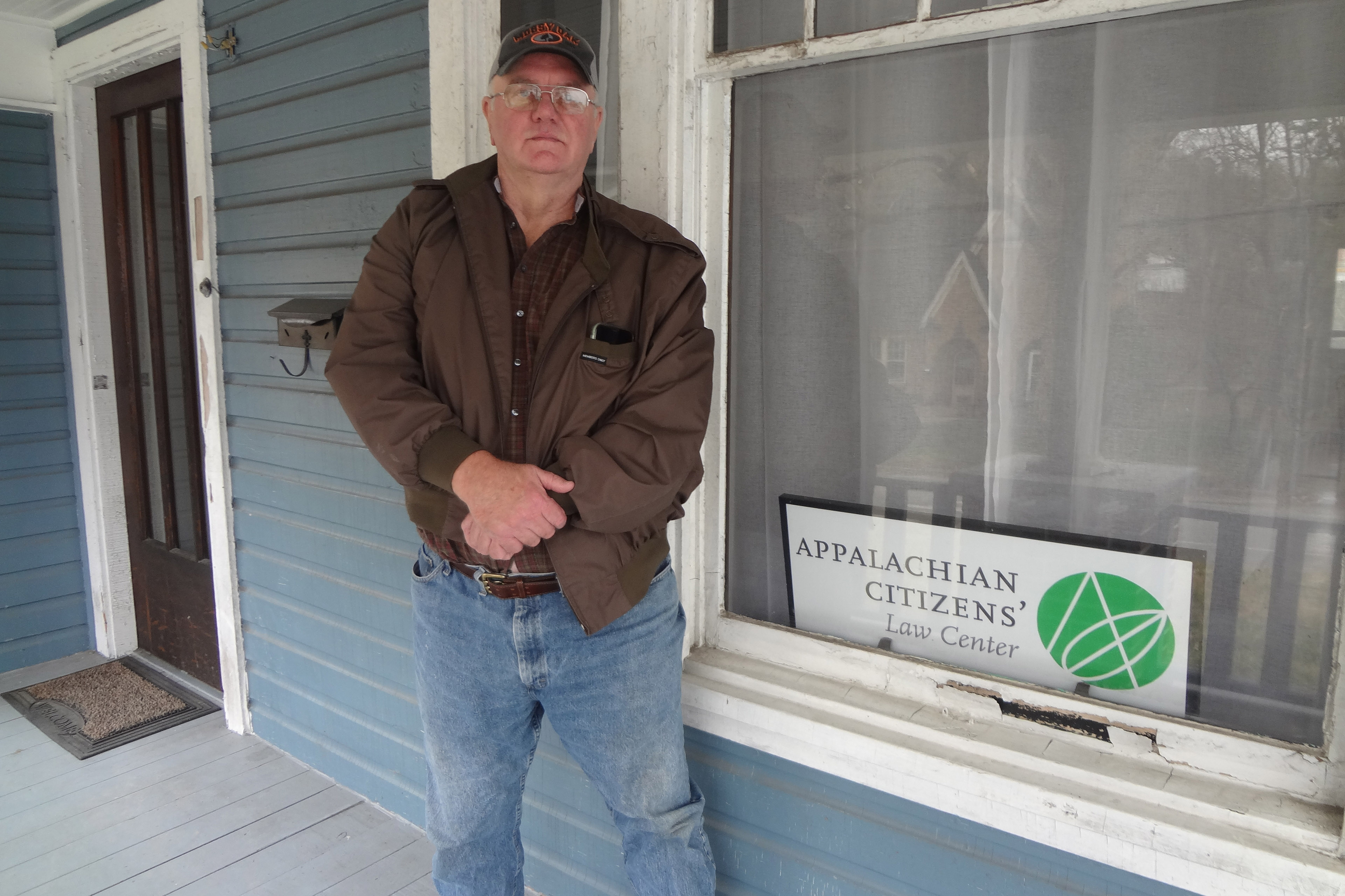 William McCool stands on his front porch with his hands crossed in front of him.
