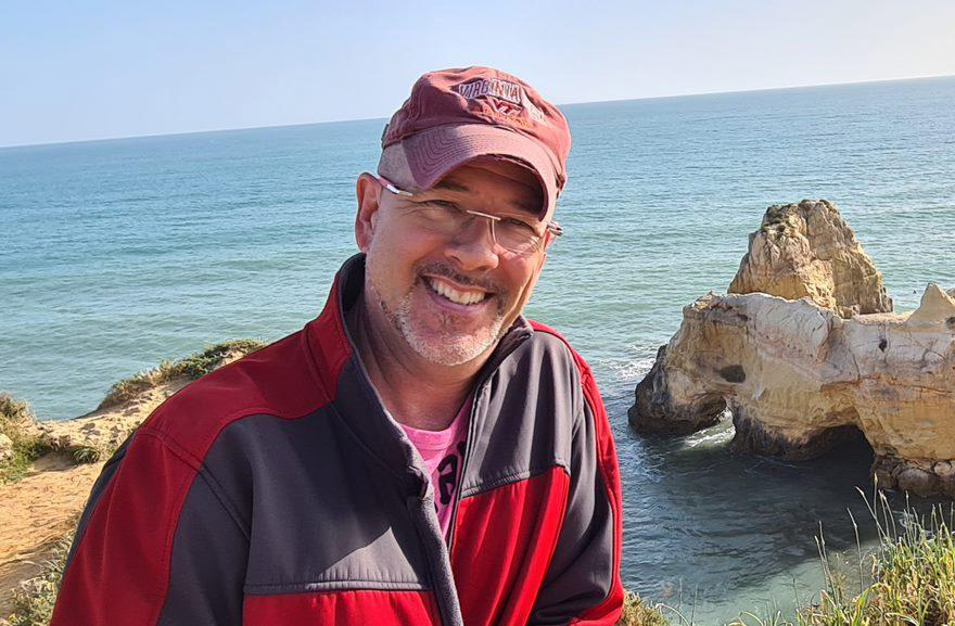 A photo of a man posing for a photo outside.