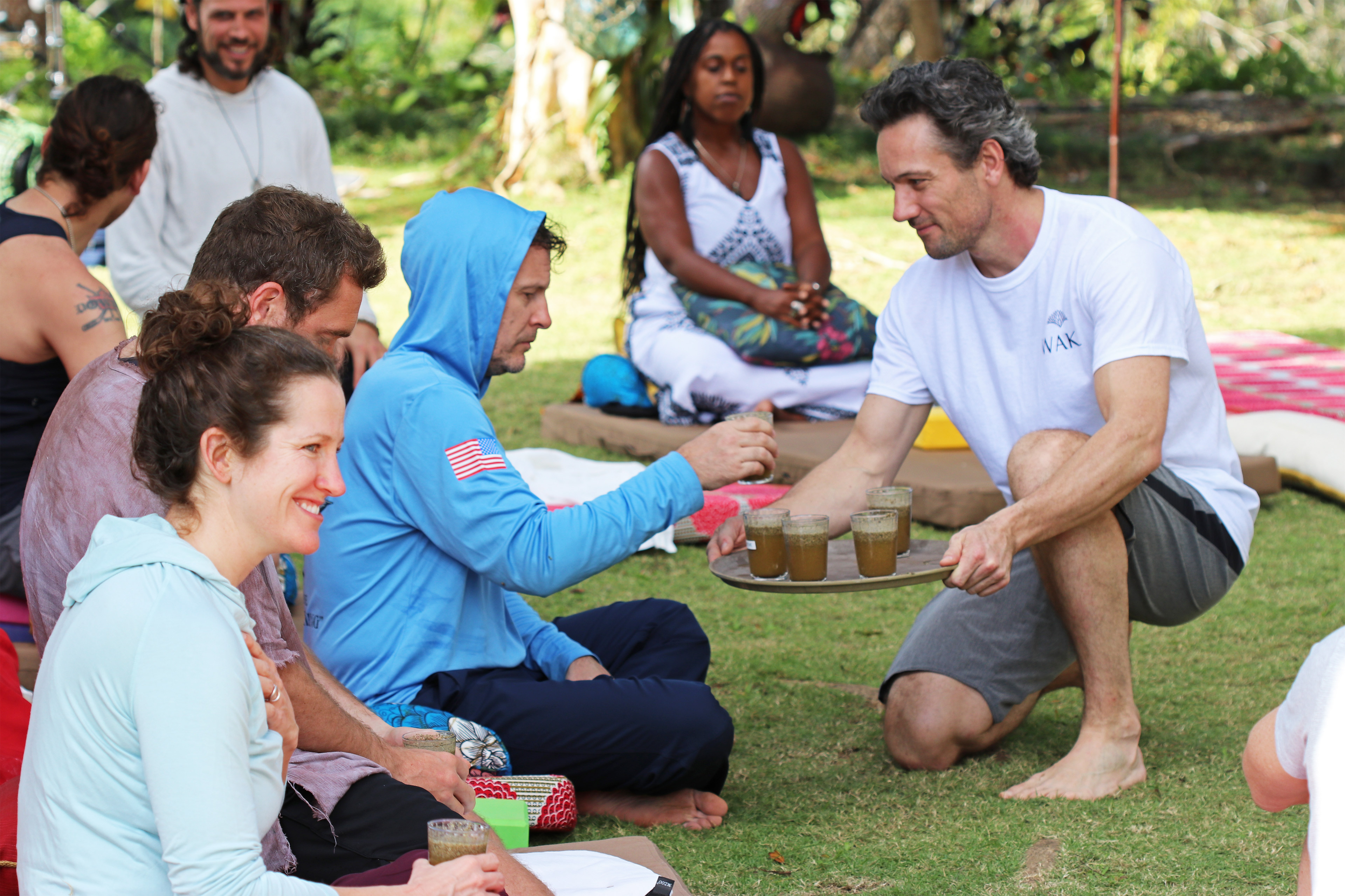 A photo of Tyler Macleod distributing glasses of magic mushrooms mixed with juice outside.