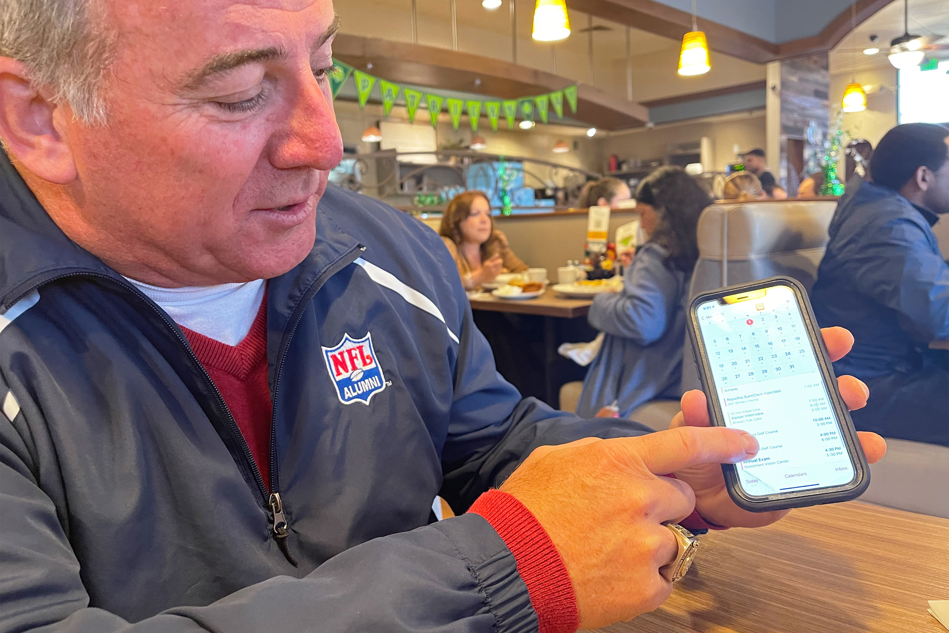 A photo of man pointing to his calendar app on his smartphone.