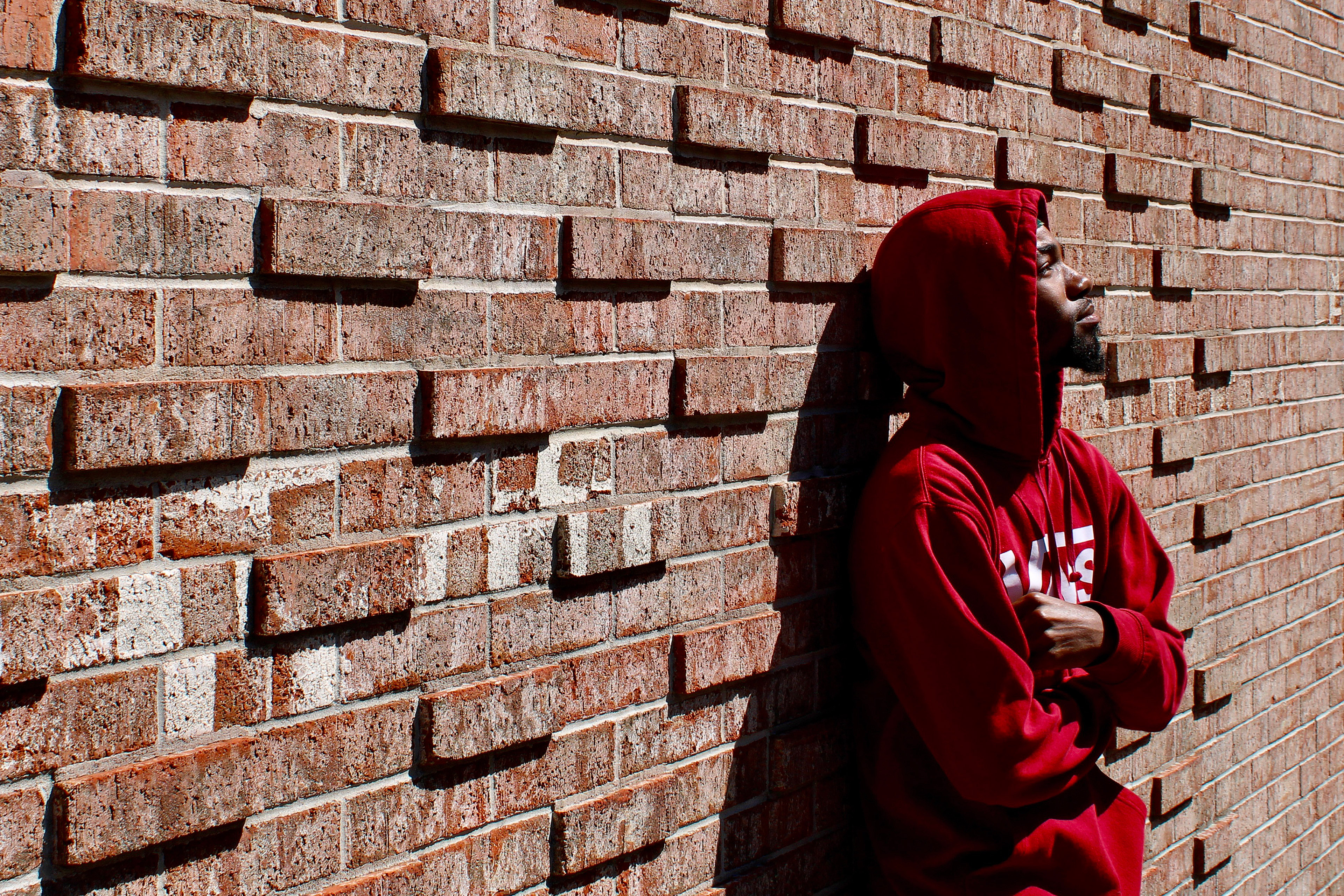A photo of Erin Brown posing for a photo by leaning on a brick wall.