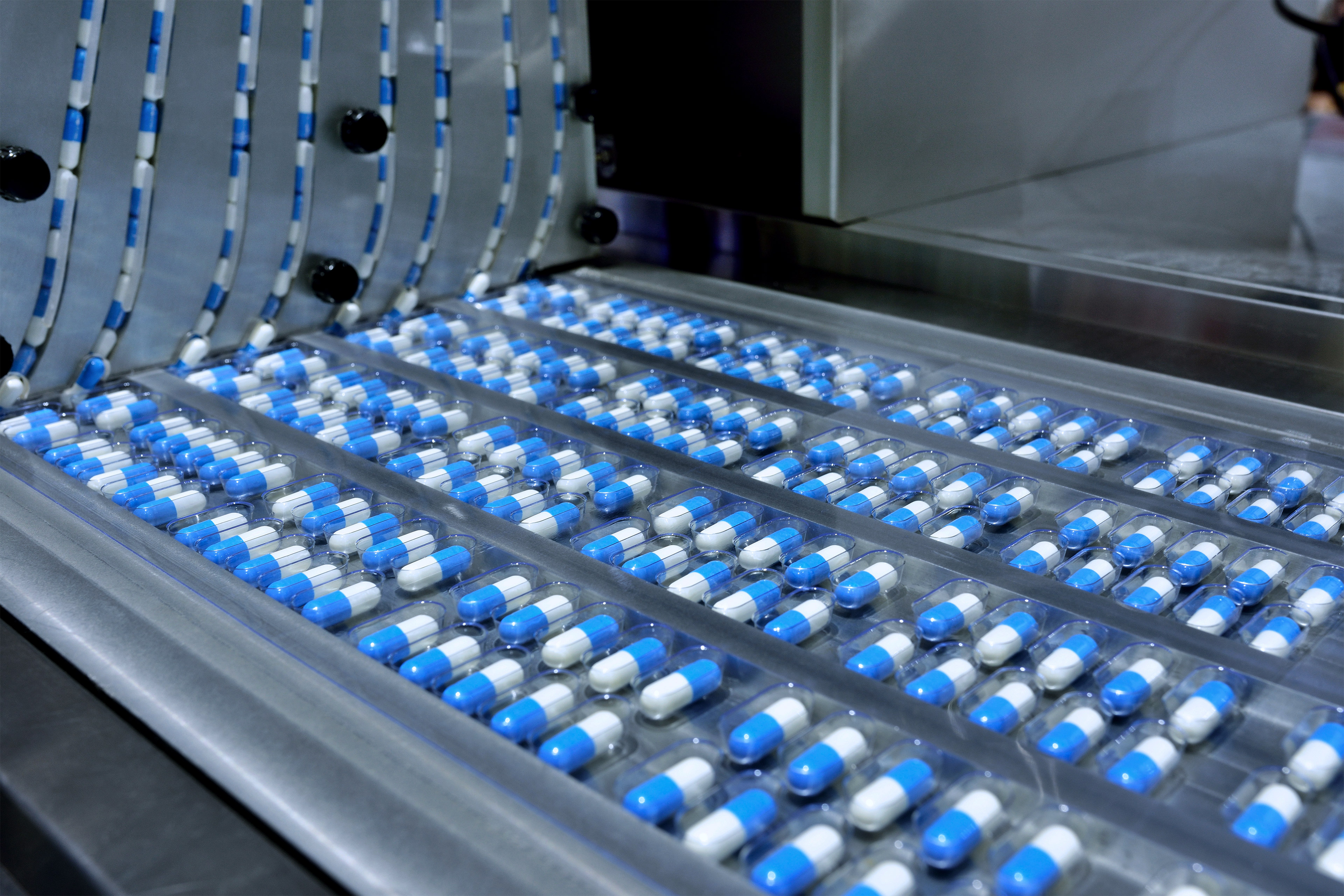A photo of packages of pills on a conveyor belt in a factory.