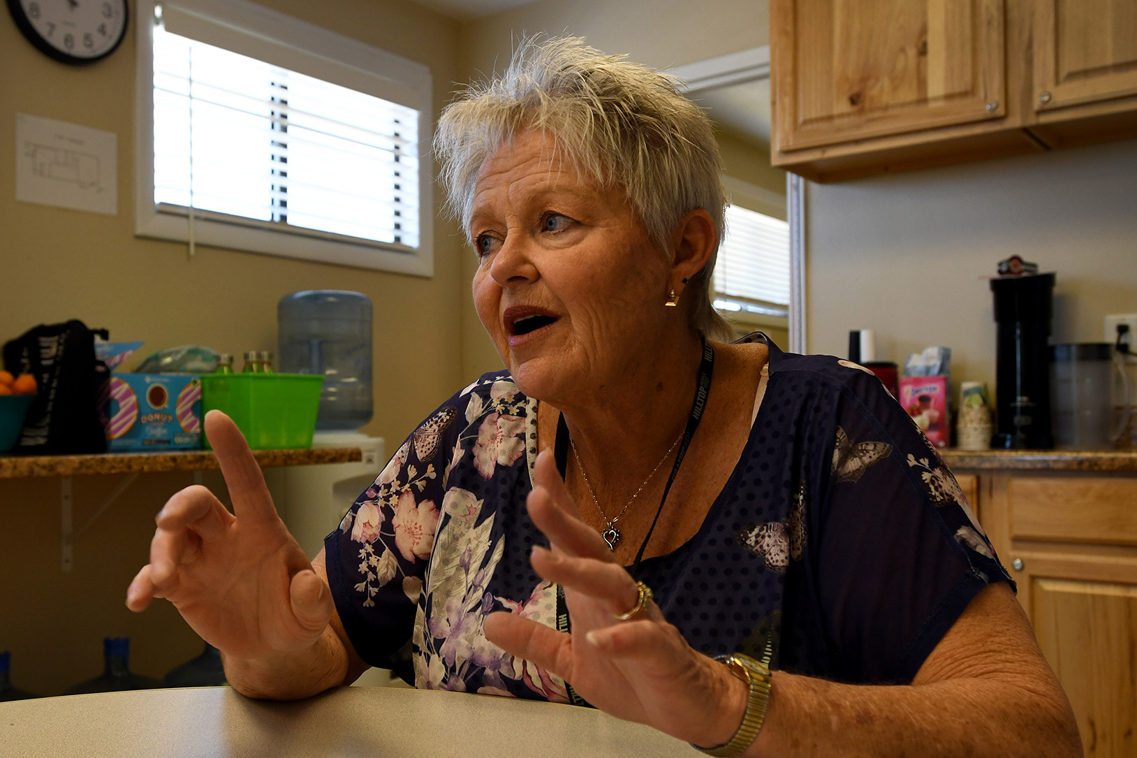 A photo of a woman speaking while sitting at a table.
