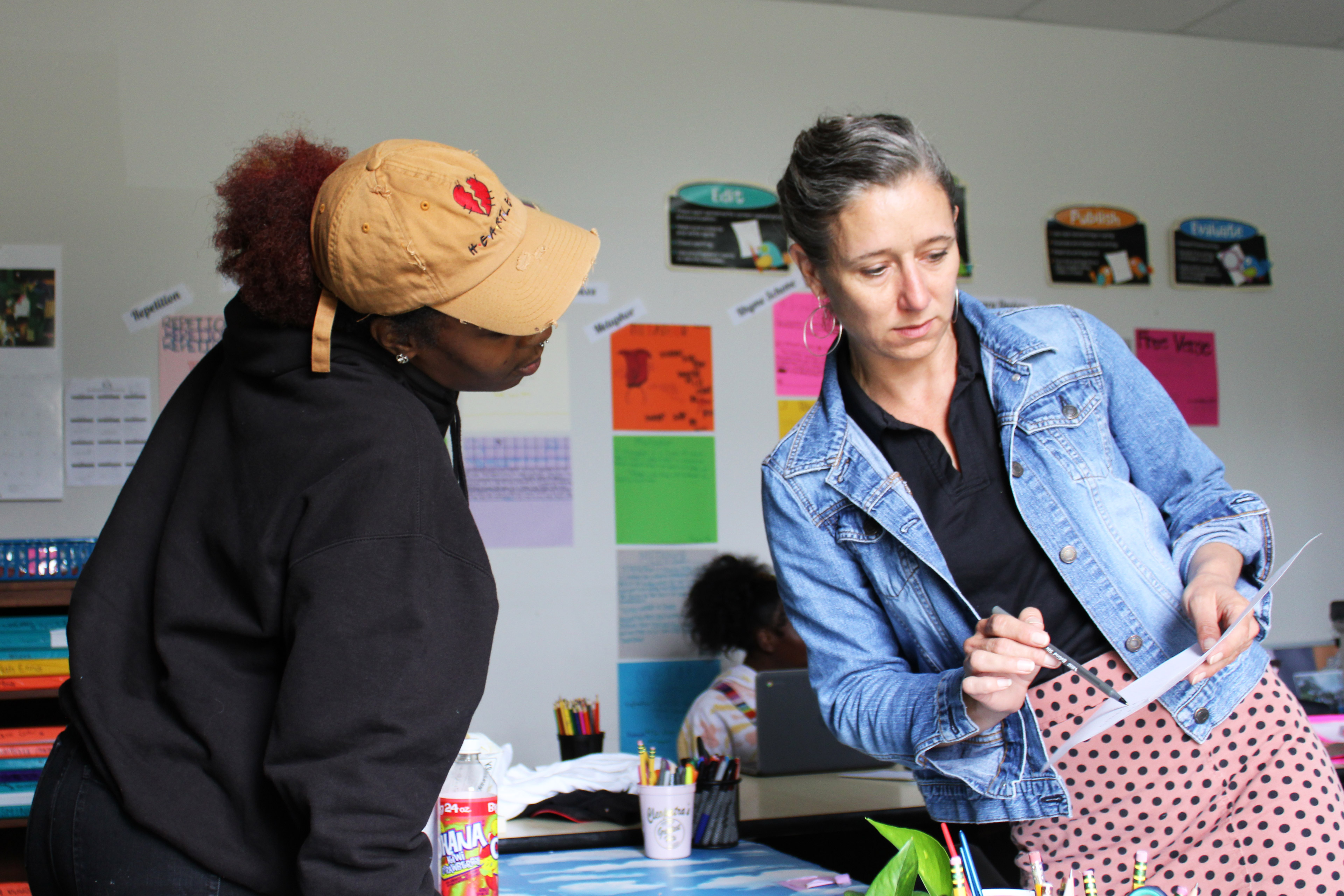 A photo of a teacher showing a female student notes on a piece of paper.