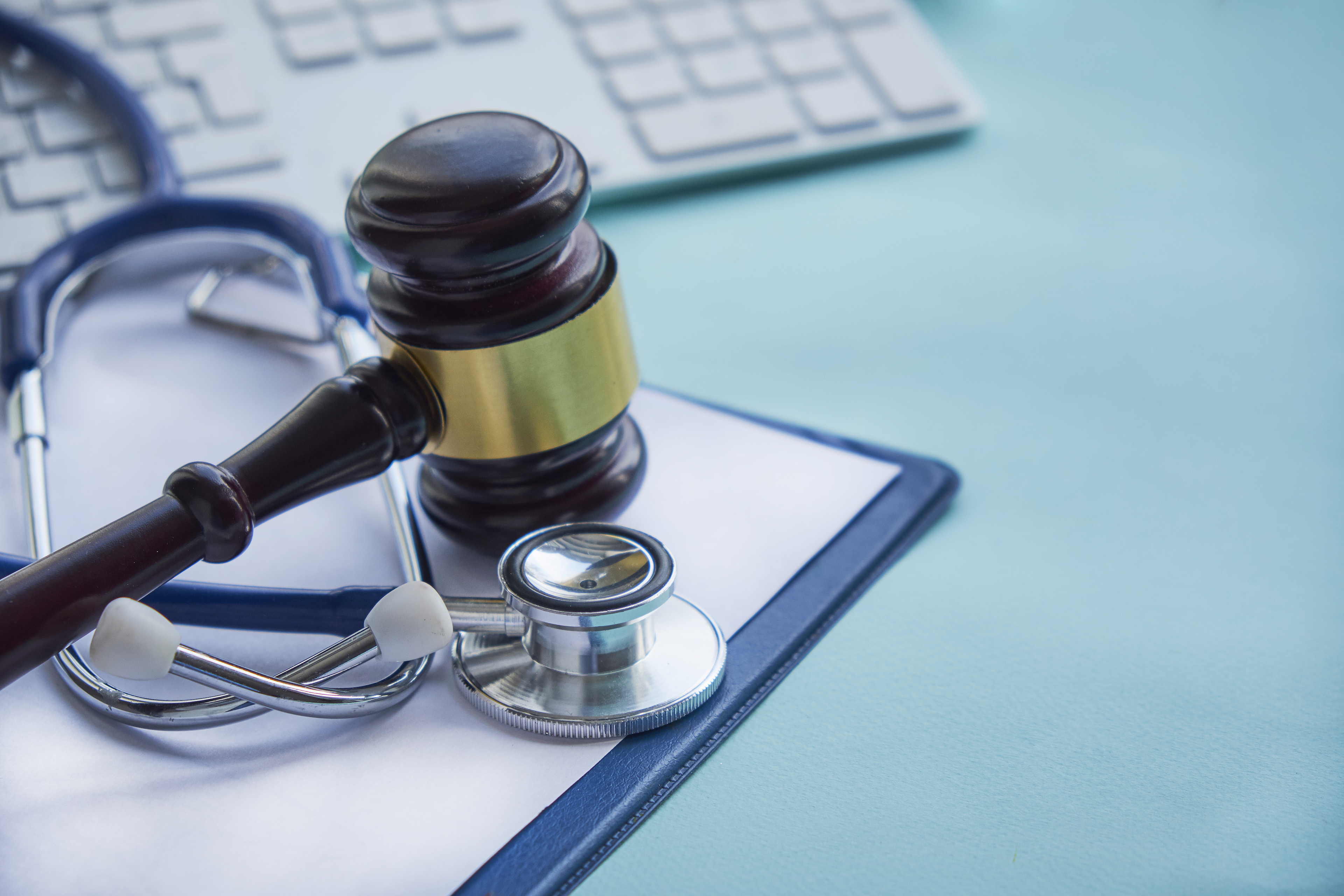 a gavel and stethoscope set on a blue table beside a computer keyboard