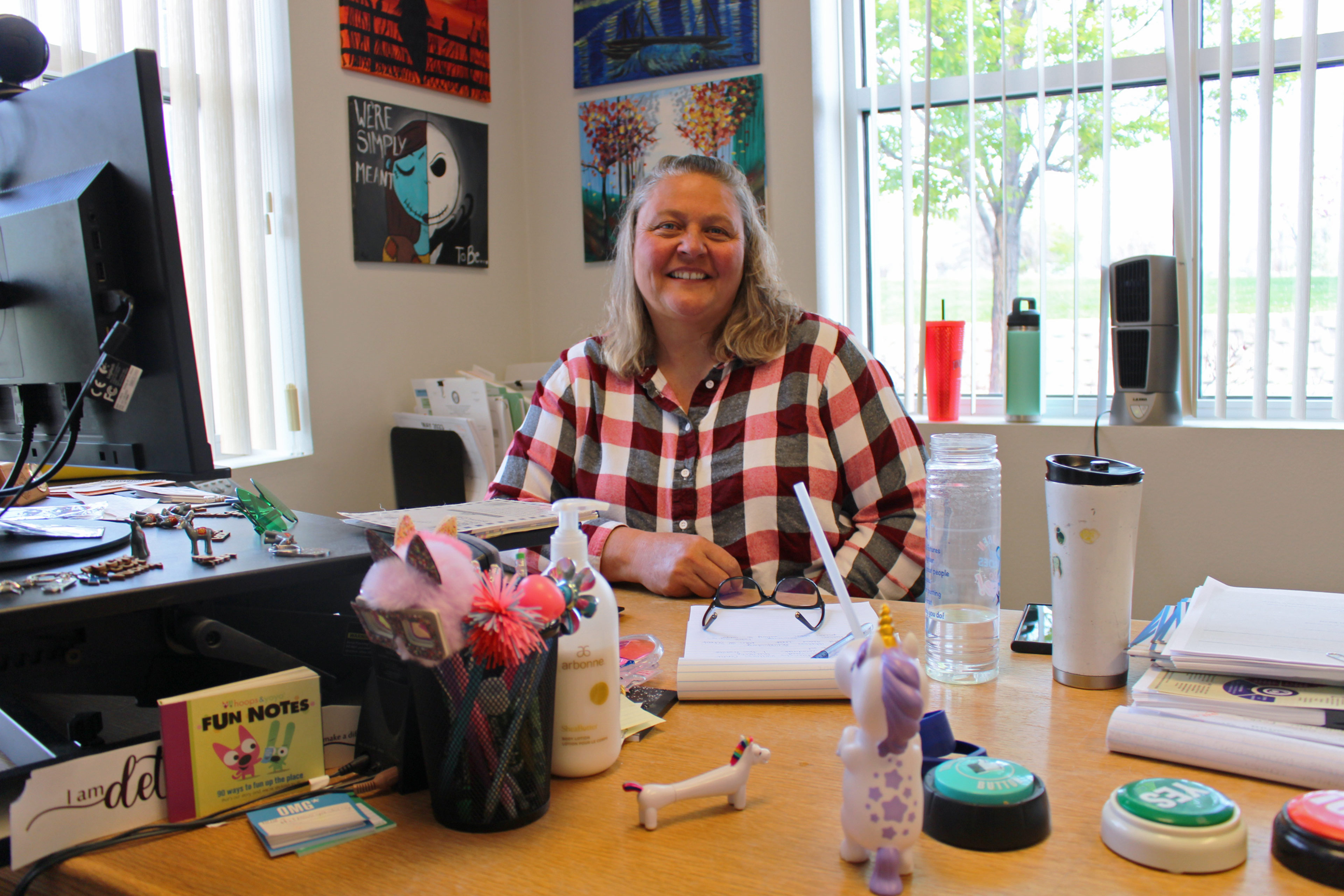 A photo of a woman sitting for a photo at an office desk.
