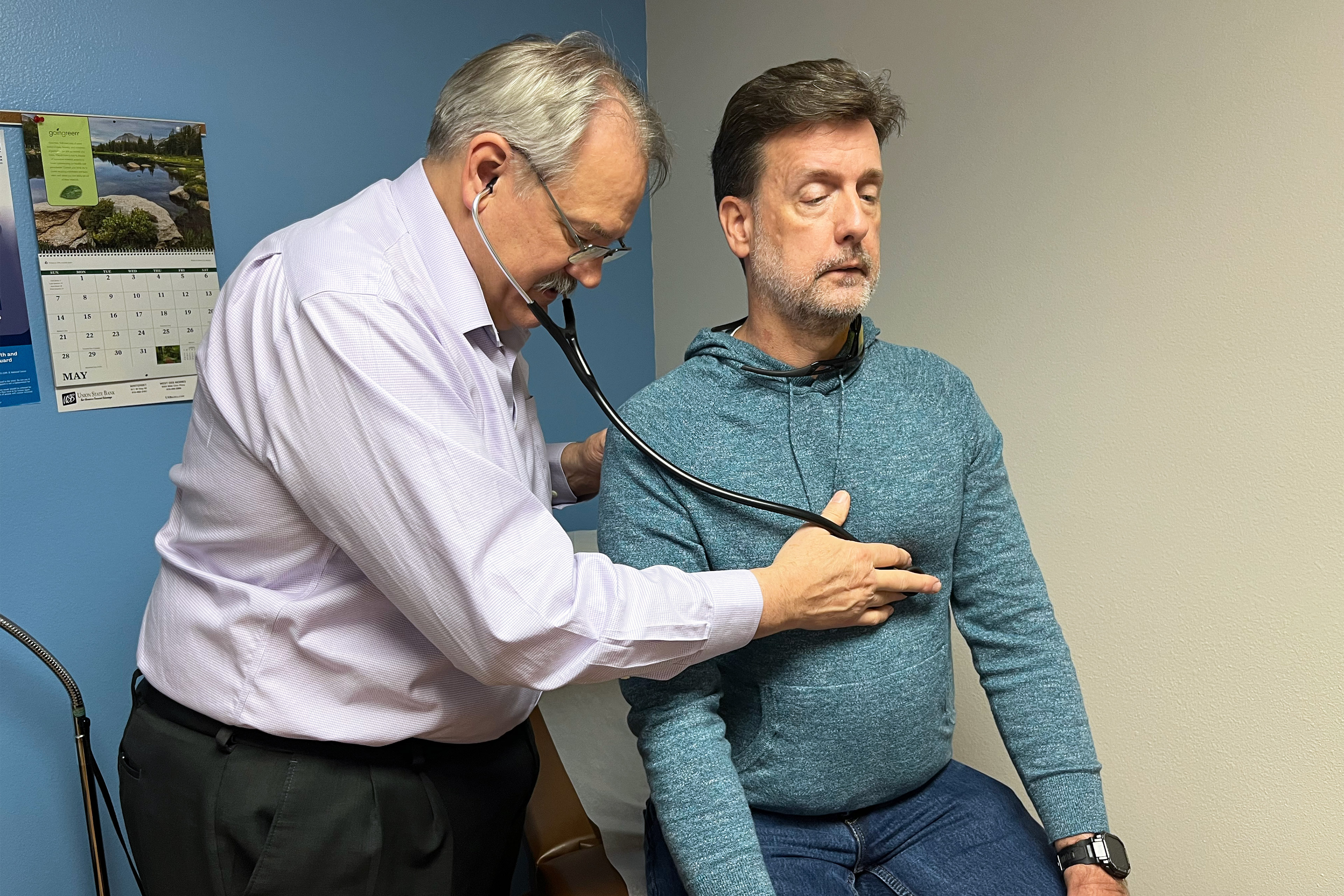 A photo of a doctor examining a male patient with a stethoscope.