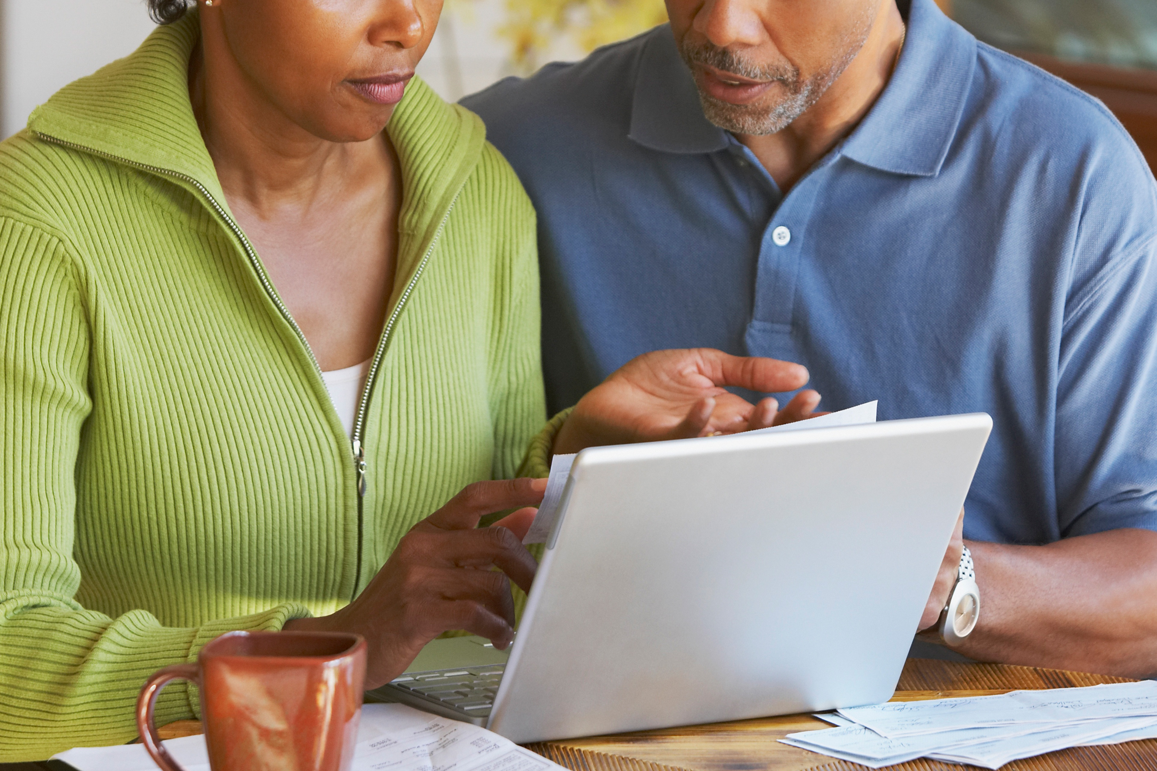 A photo of a couple looking at bills and a laptop together.