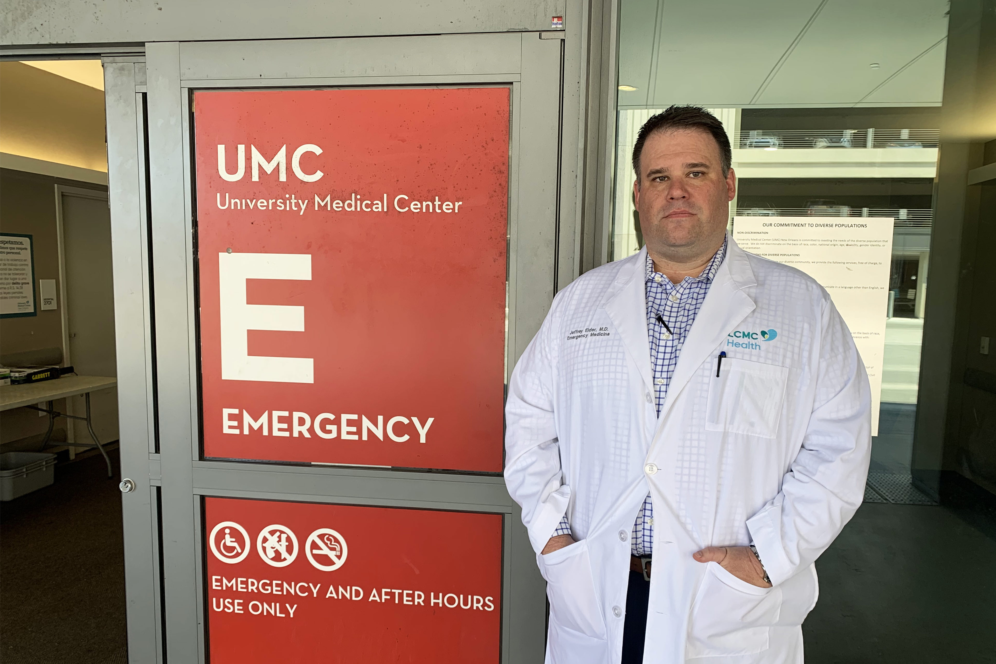 A photo of a man standing in front of a hospital door.