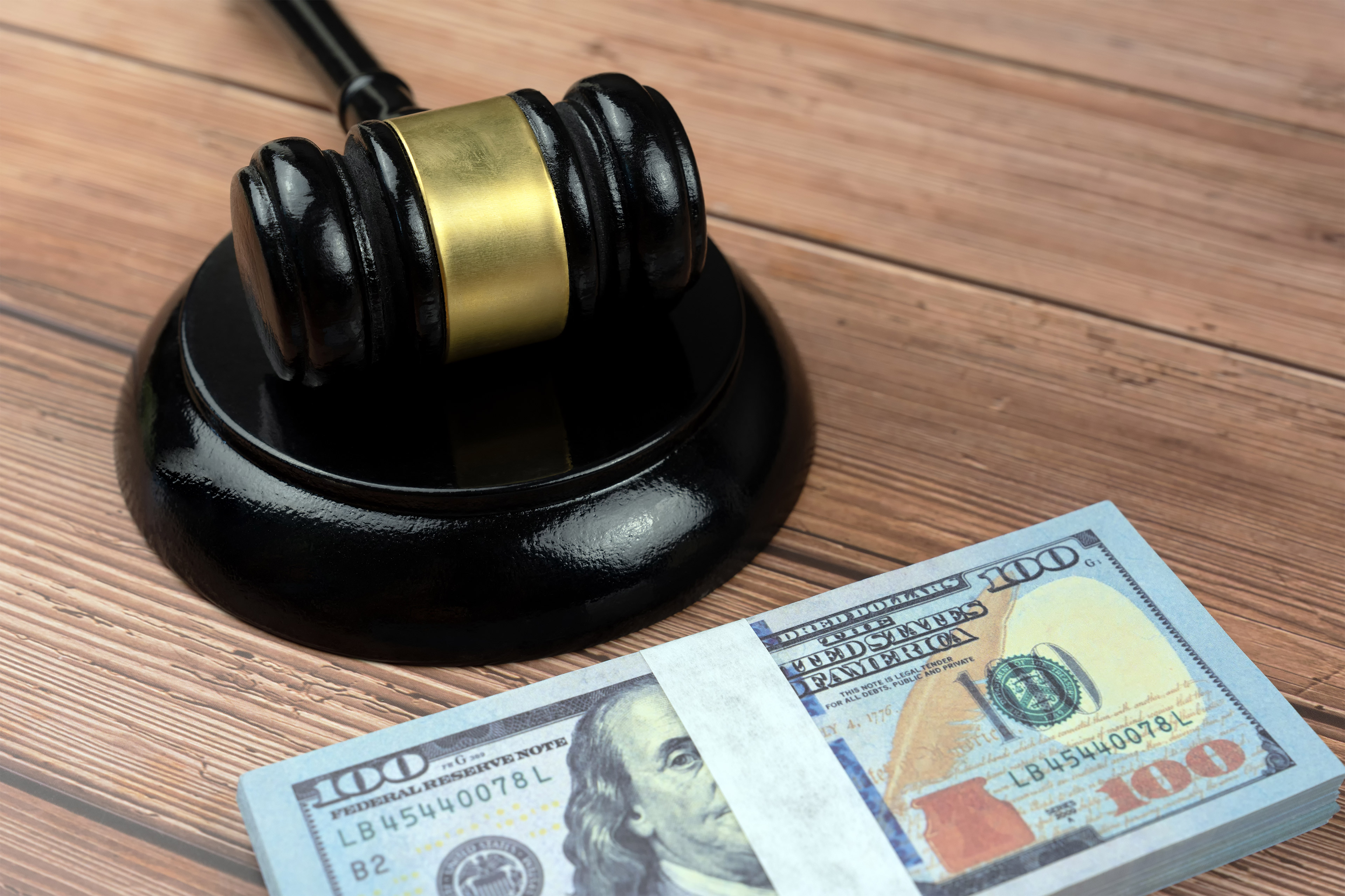 A photo of a gavel resting next to a stack of money.