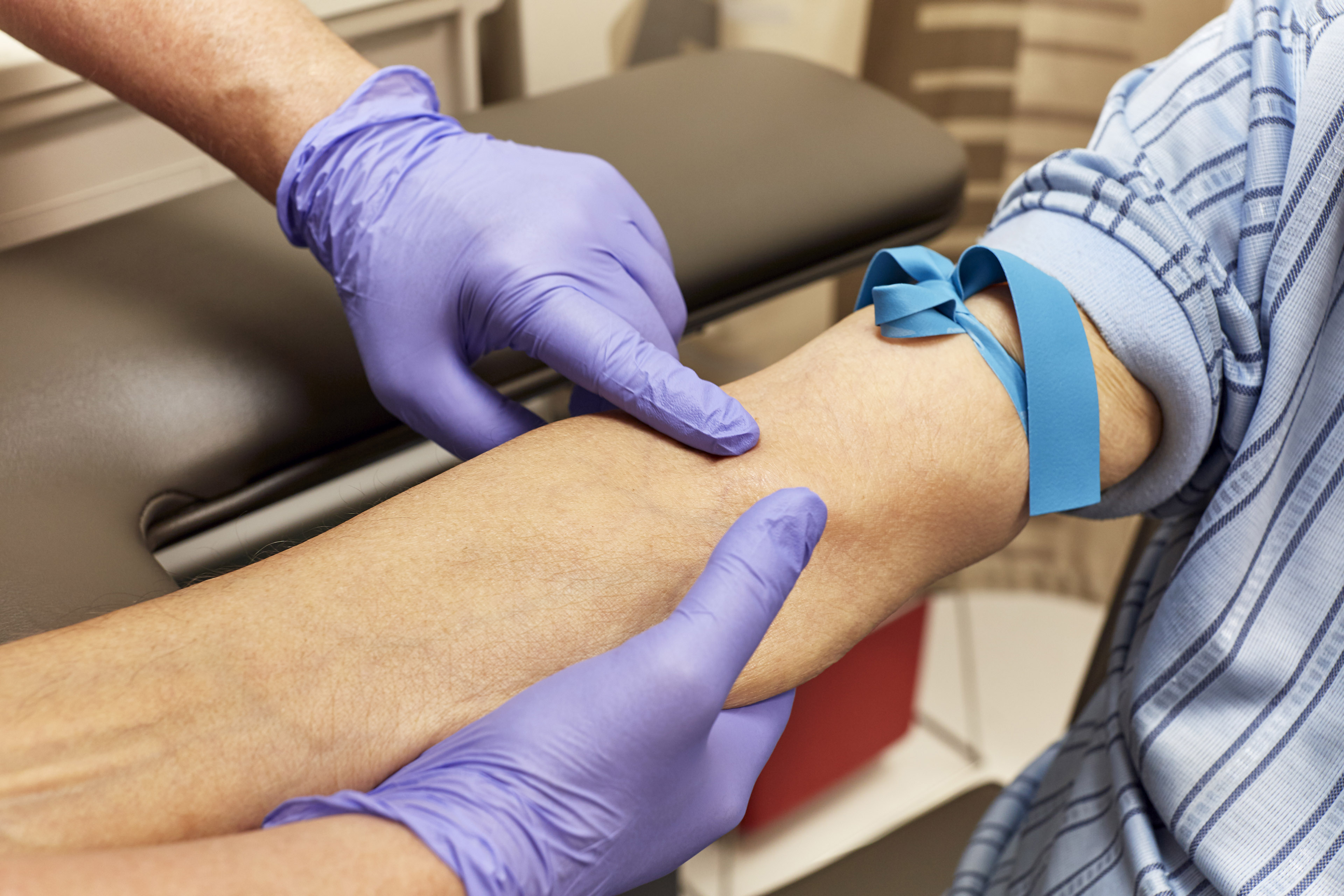 A health care technician preps the arm of a senior adult for a blood draw.