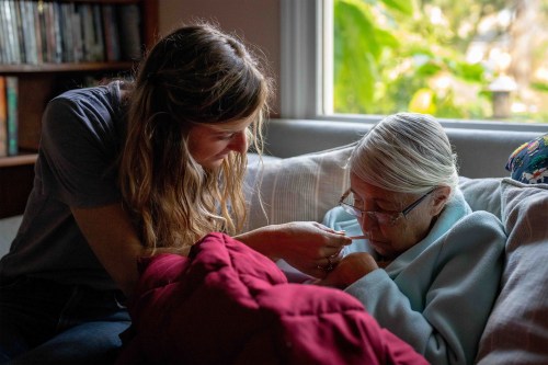 A photo of a caretaker aiding an elderly woman.