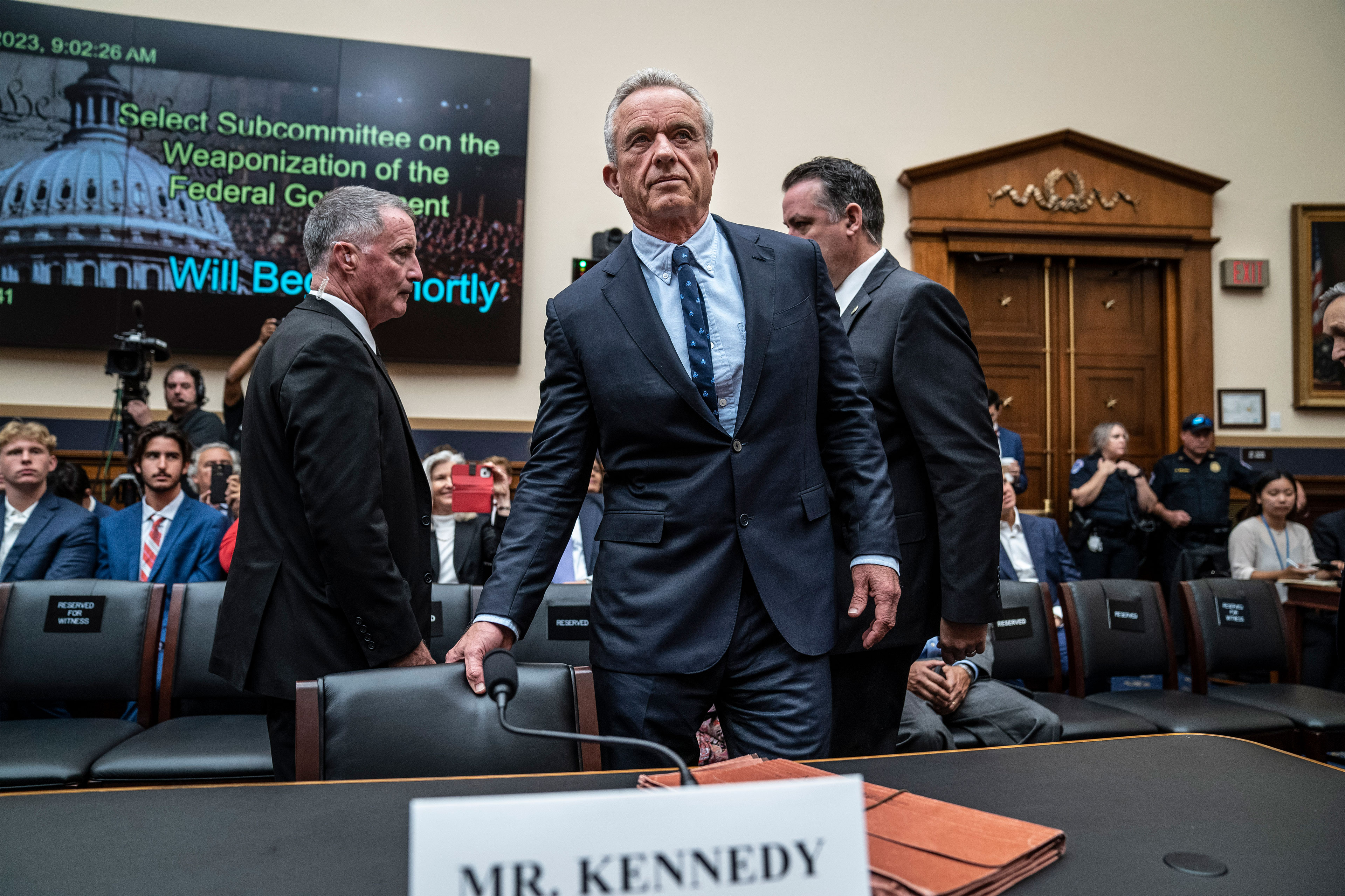 A photo of Robert F. Kennedy taking a seat during a House subcommittee hearing.