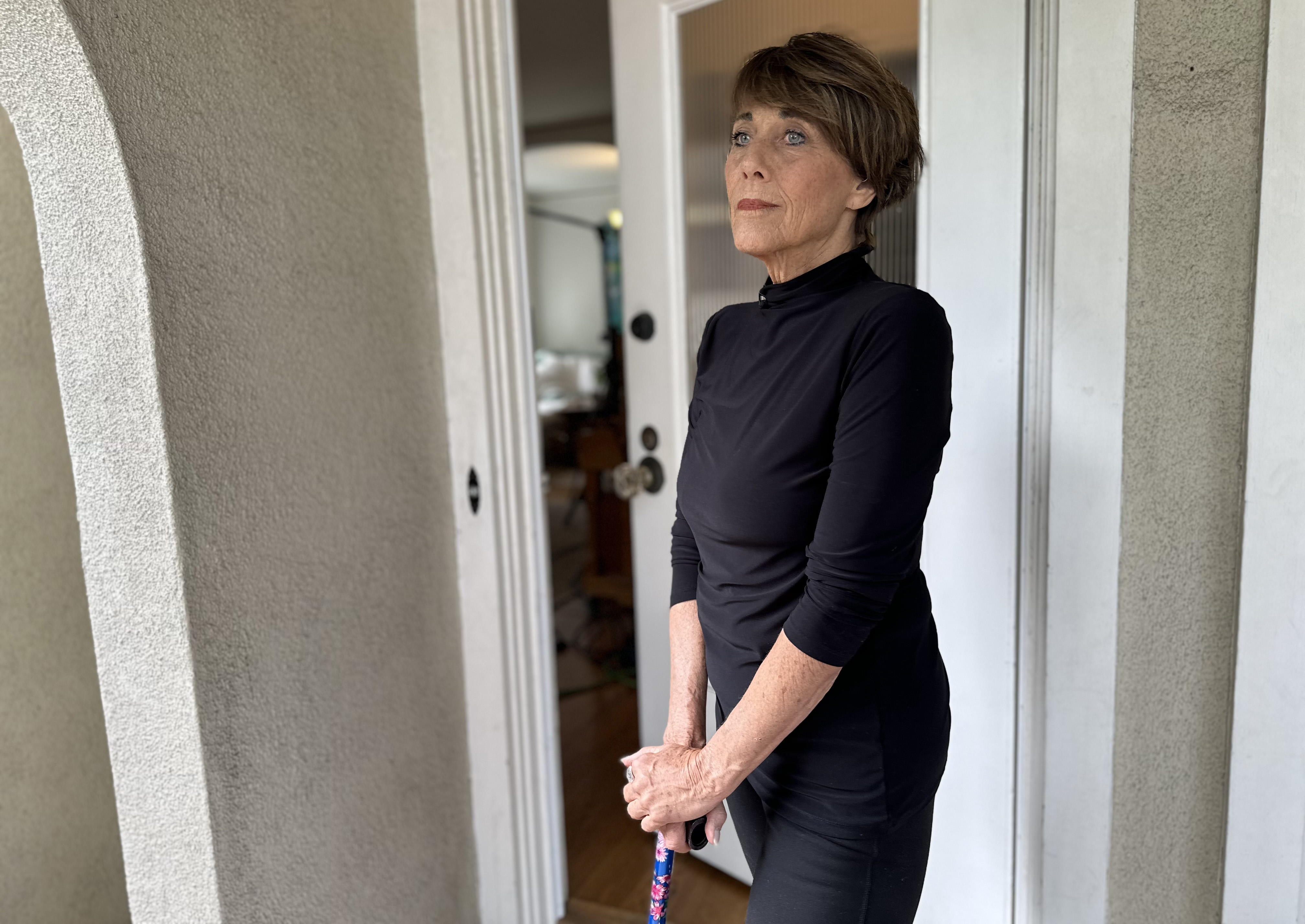 A photo of a woman posing for a portrait, propping herself up with a cane.
