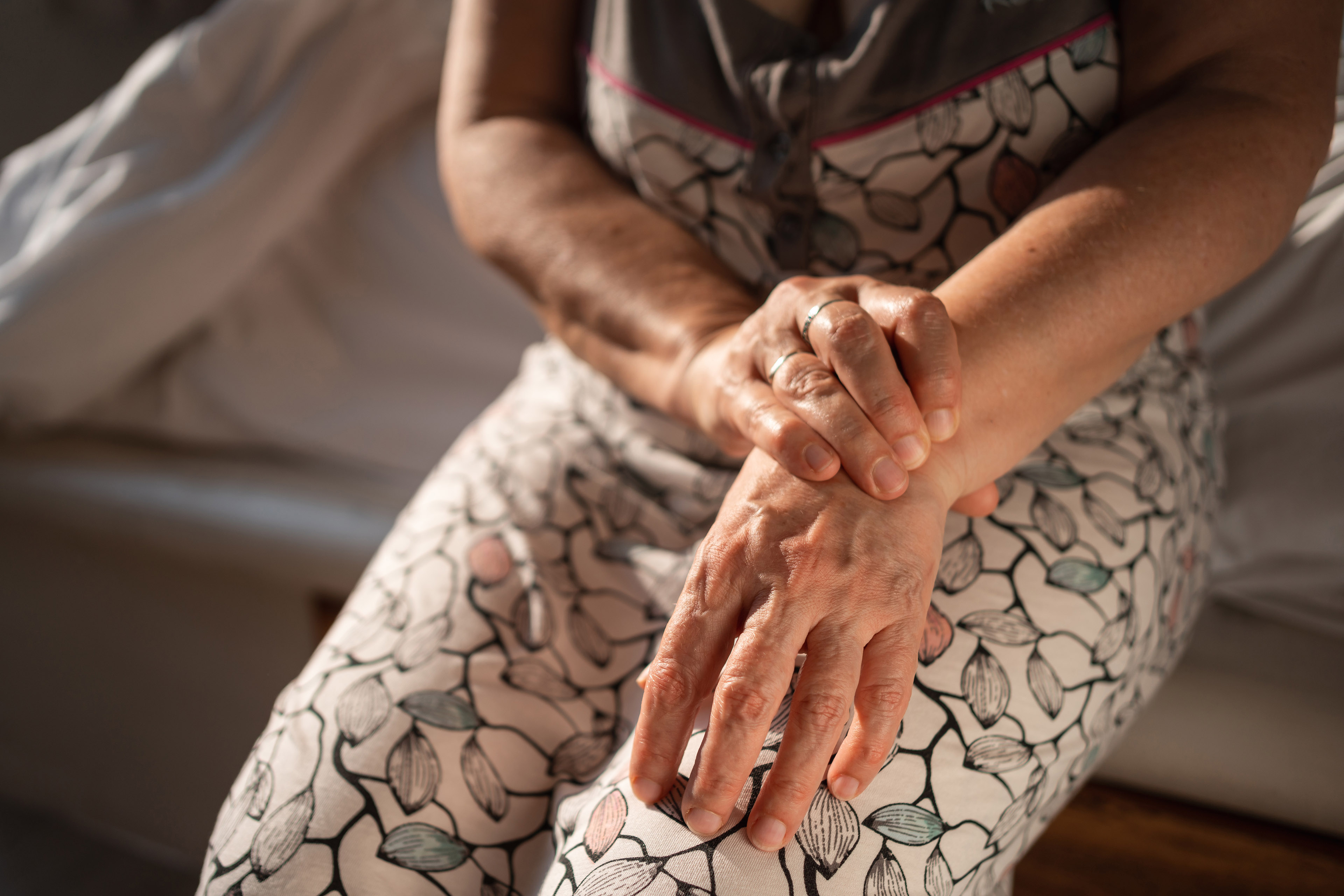 An unrecognizable senior woman massages her wrist in an effort to relieve pain or discomfort.