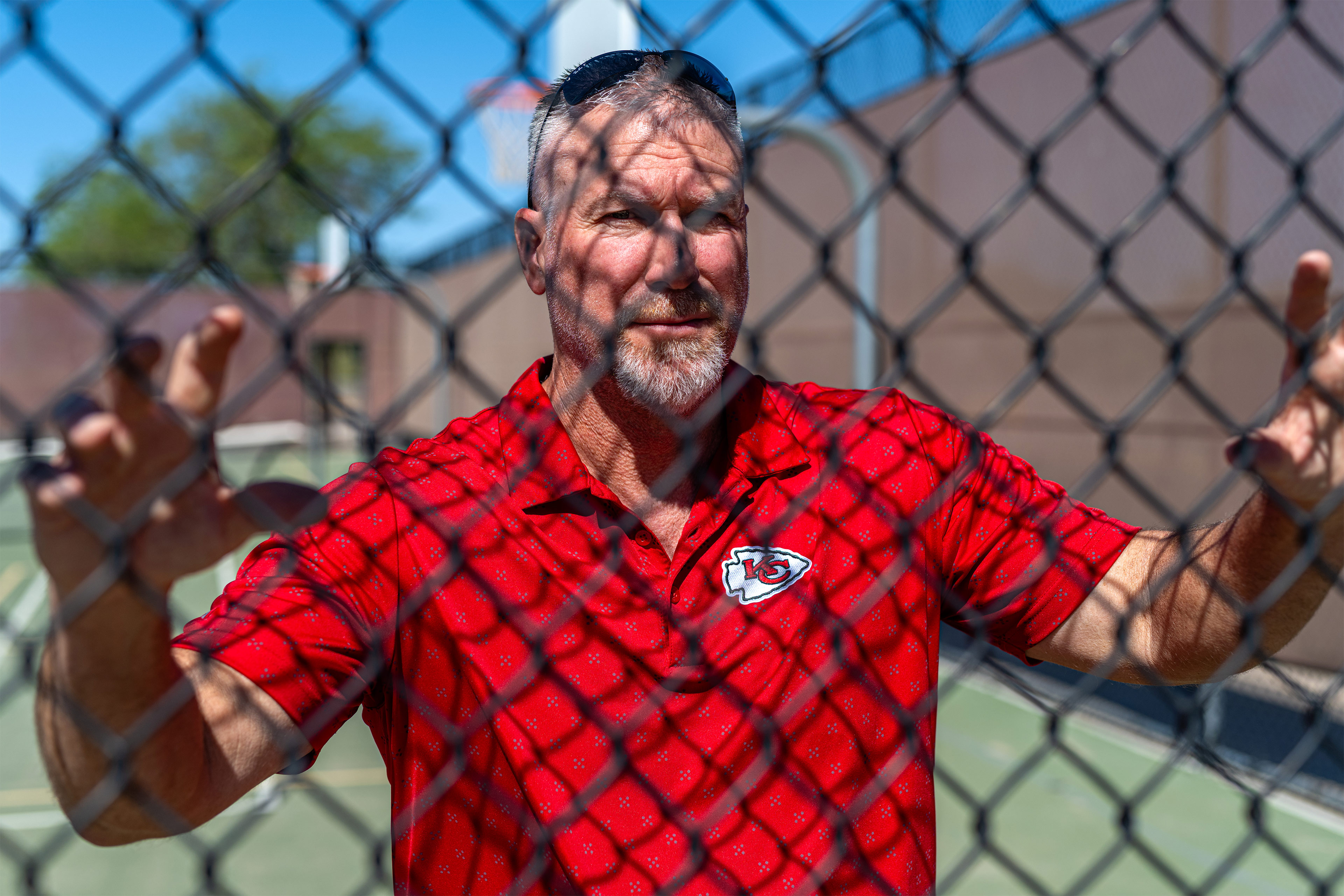 A photo of Bradley Little posing for a portrait behind a wire fence.