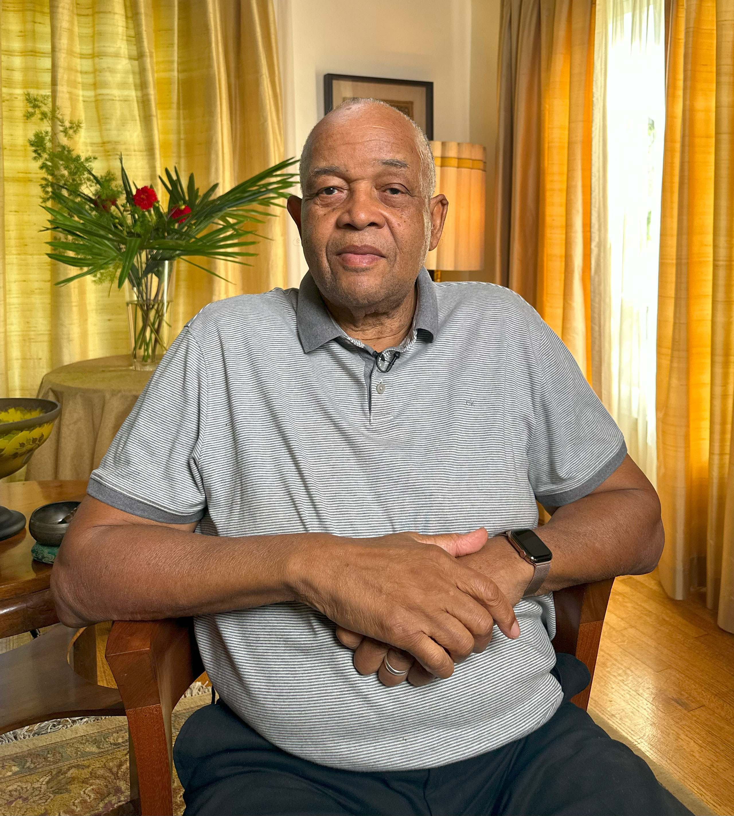 A photo of a man posing for a portrait while sitting in a chair.