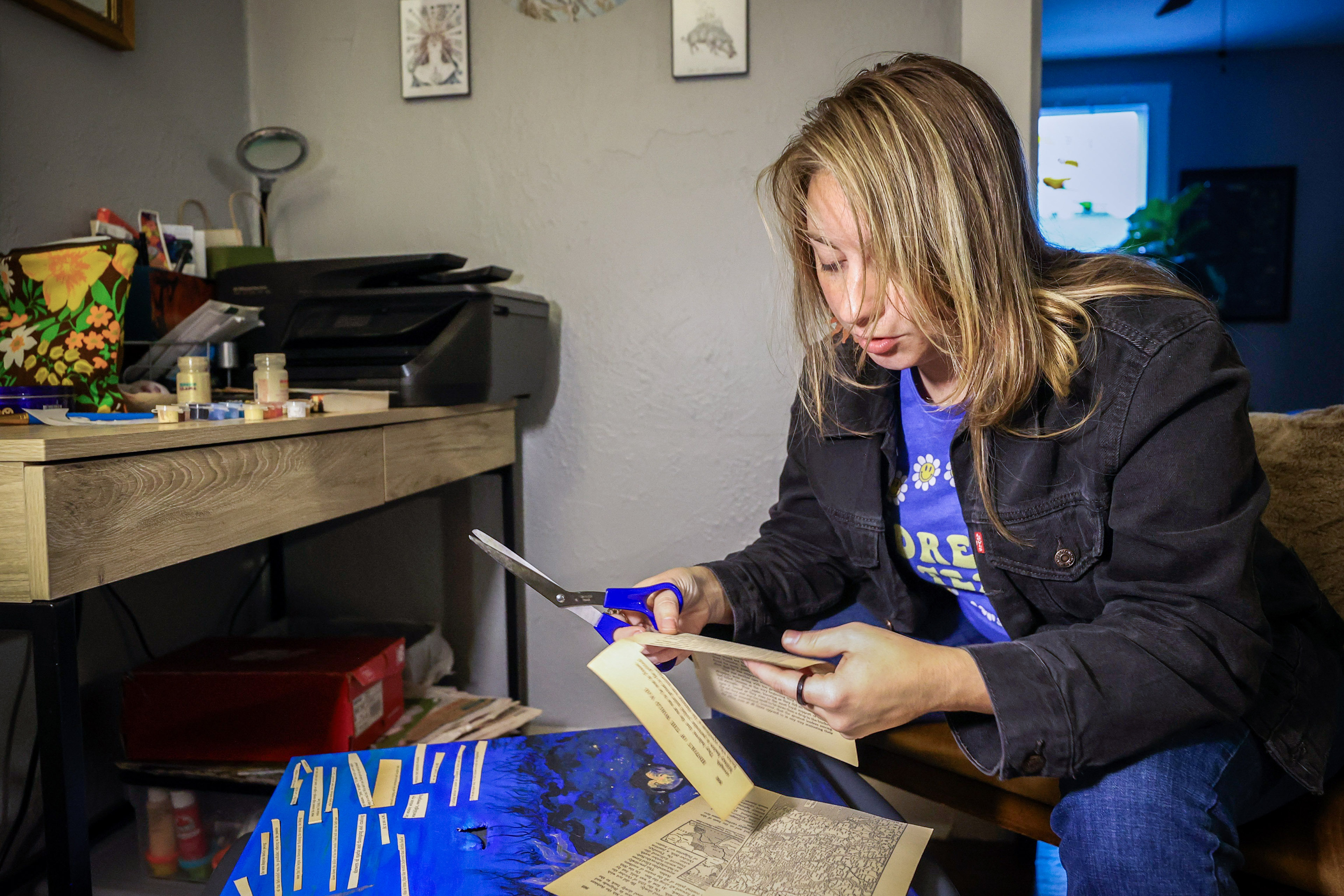 Nina Shand works on her art at home in St. Petersburg, Florida. She is cutting up pages from an old book, picking out words and sentence fragments.