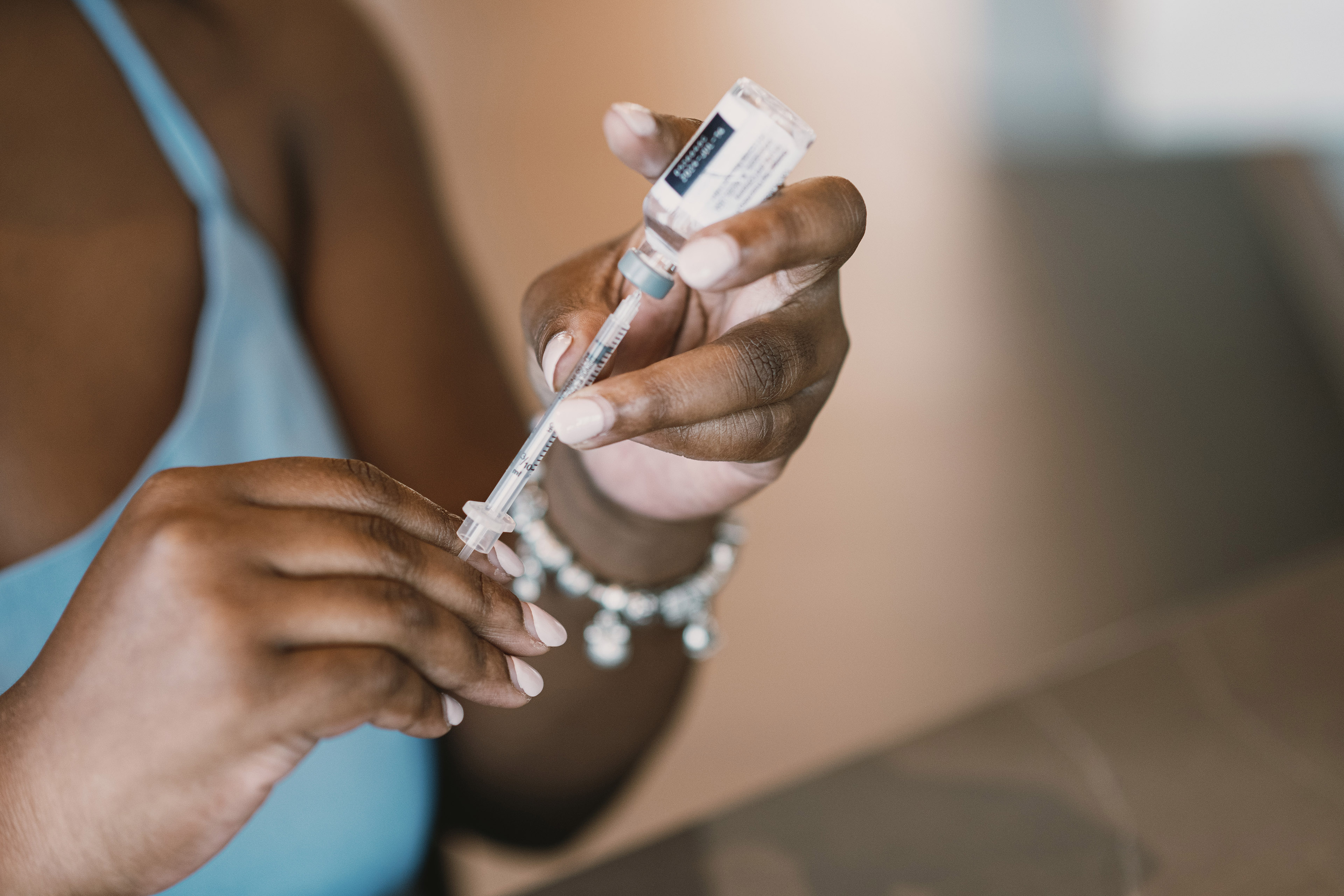 Mila Clarke inserts a syringe into a vial of insulin.