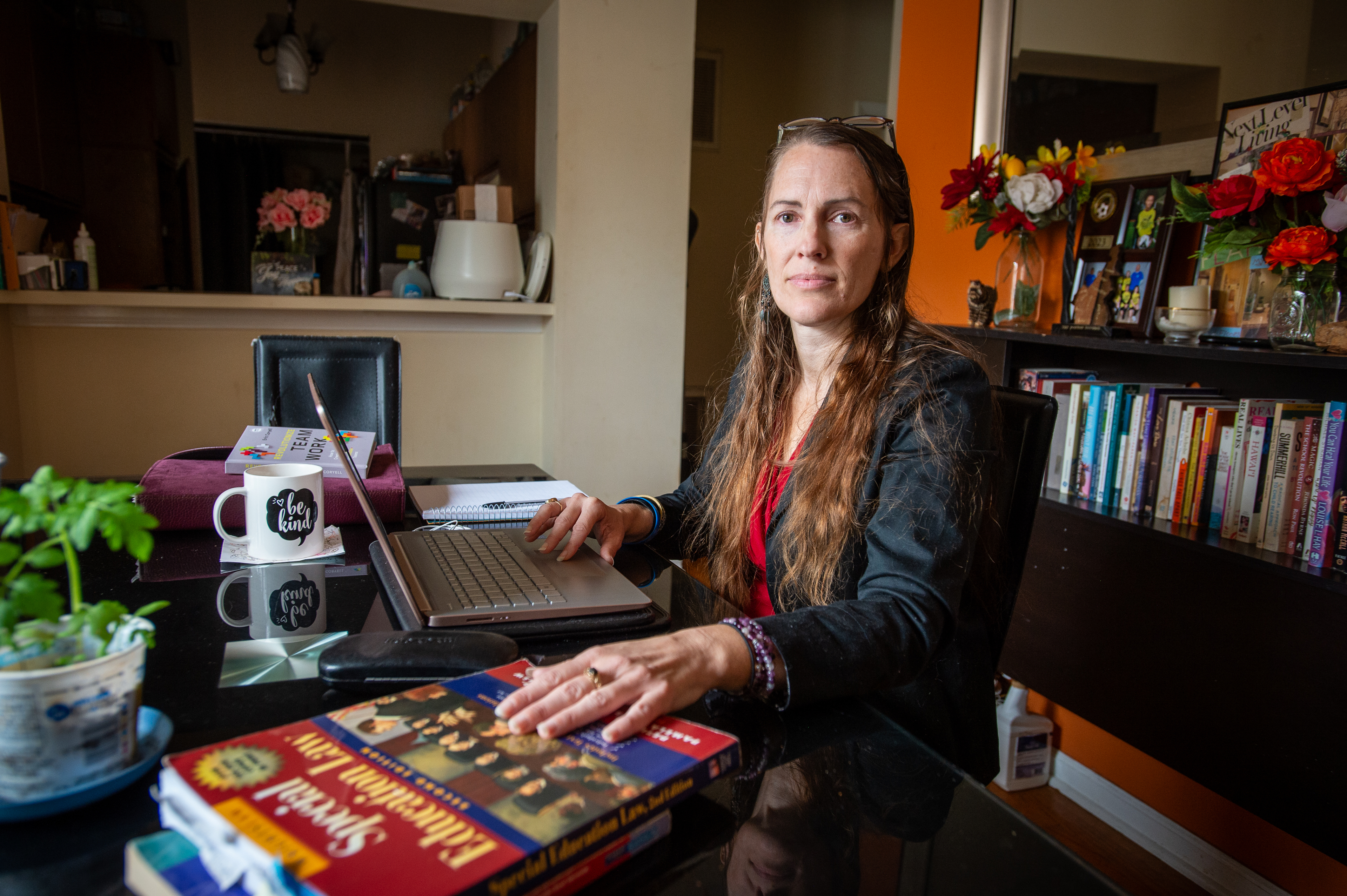 A portrait of Hannah Russell sitting at her computer desk. One hand is on her computer while her other hand is resting on a book titled, "Special Education Law."