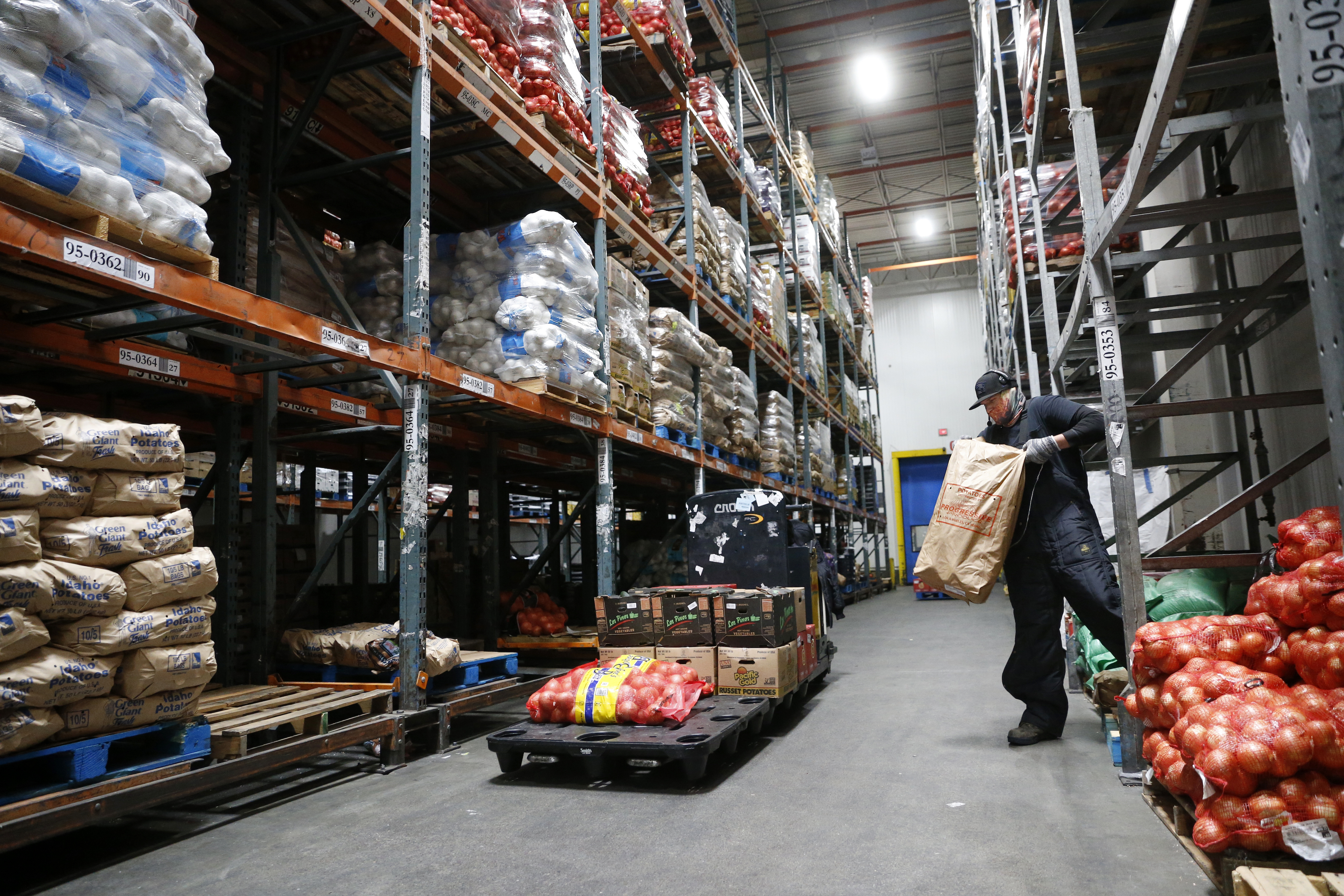 A man works in a large warehouse moving bags of produce