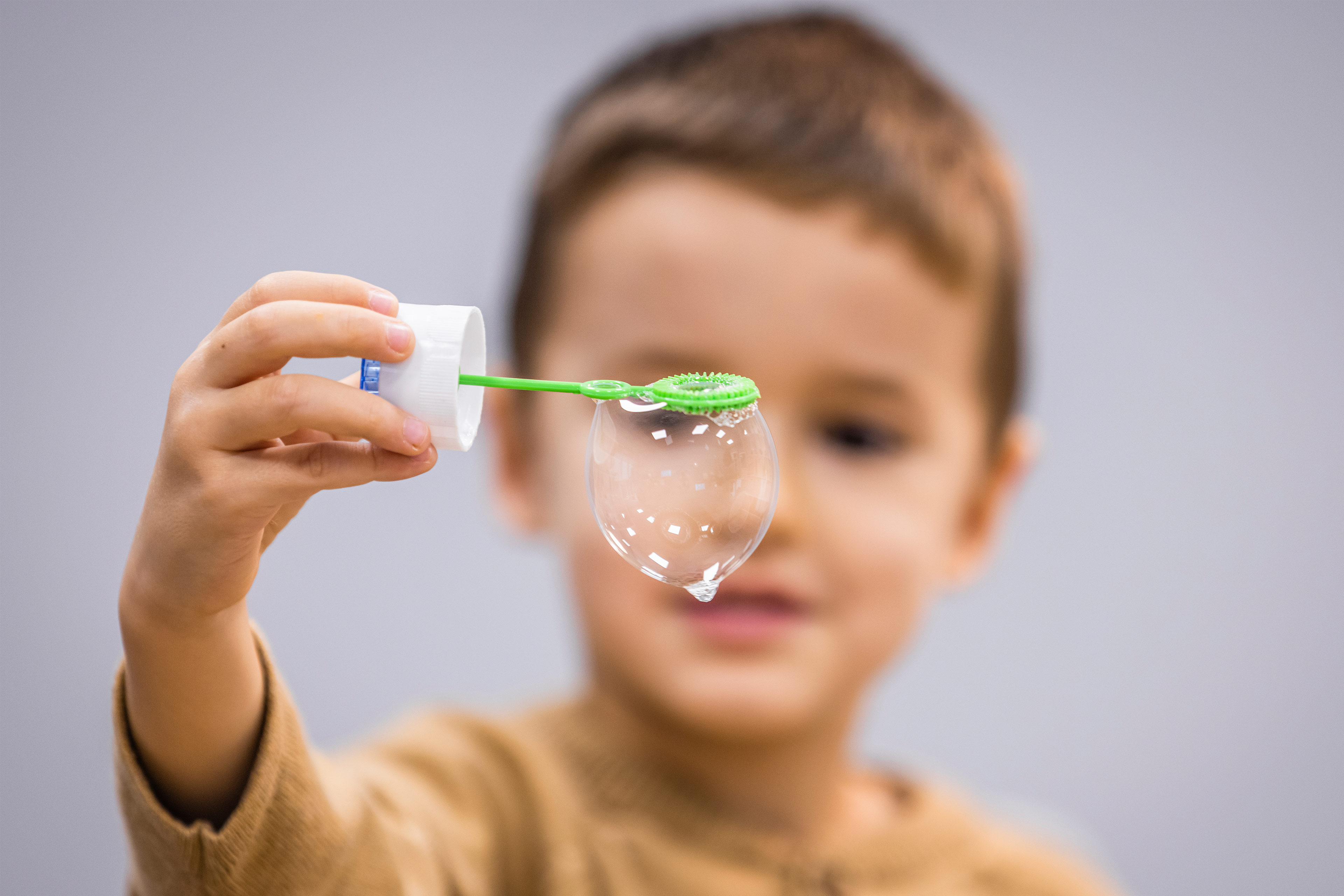 A photo of a young boy holding a bubble wand indoors.