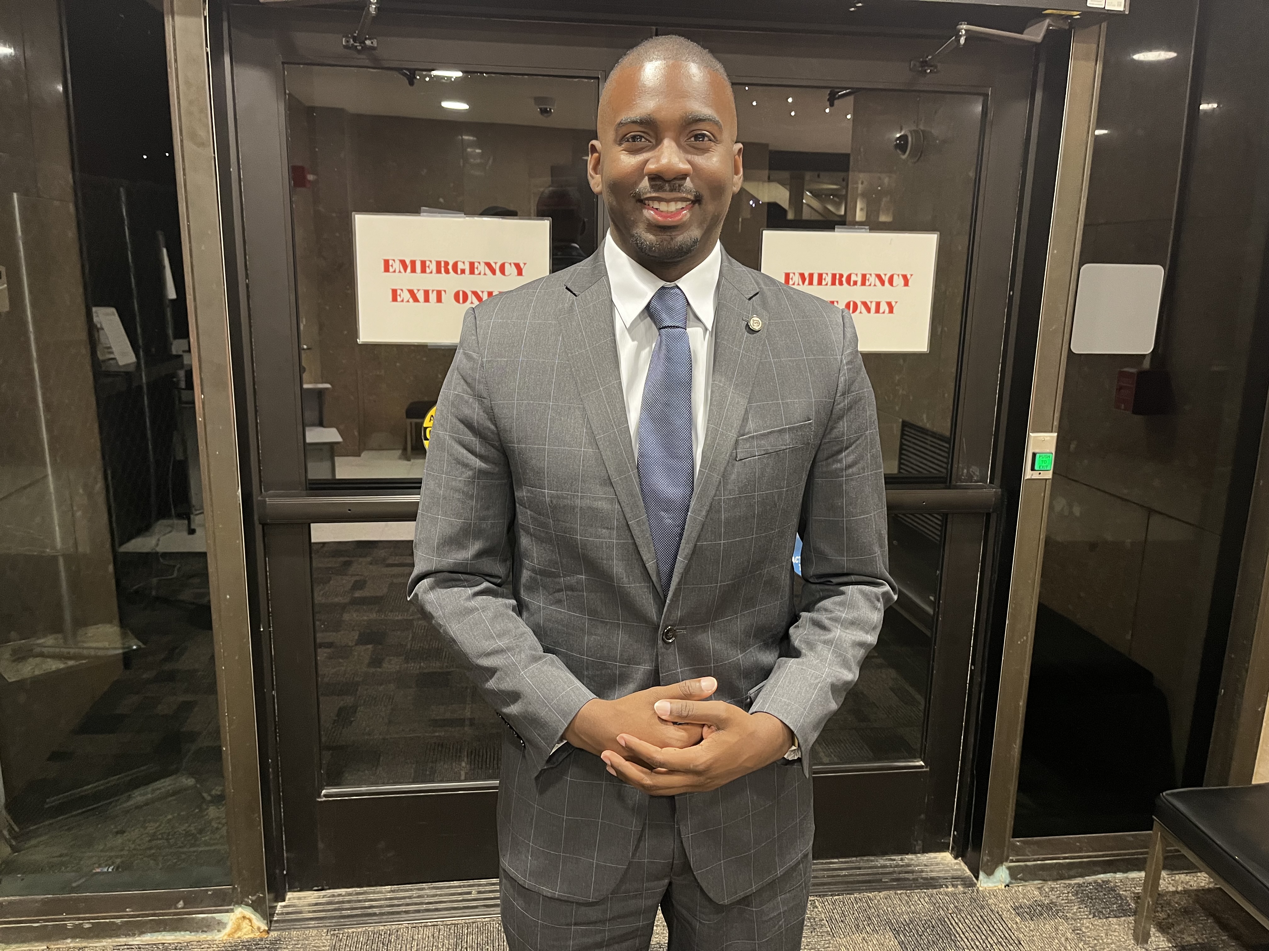 A man in a suit and tie smiles for a photo