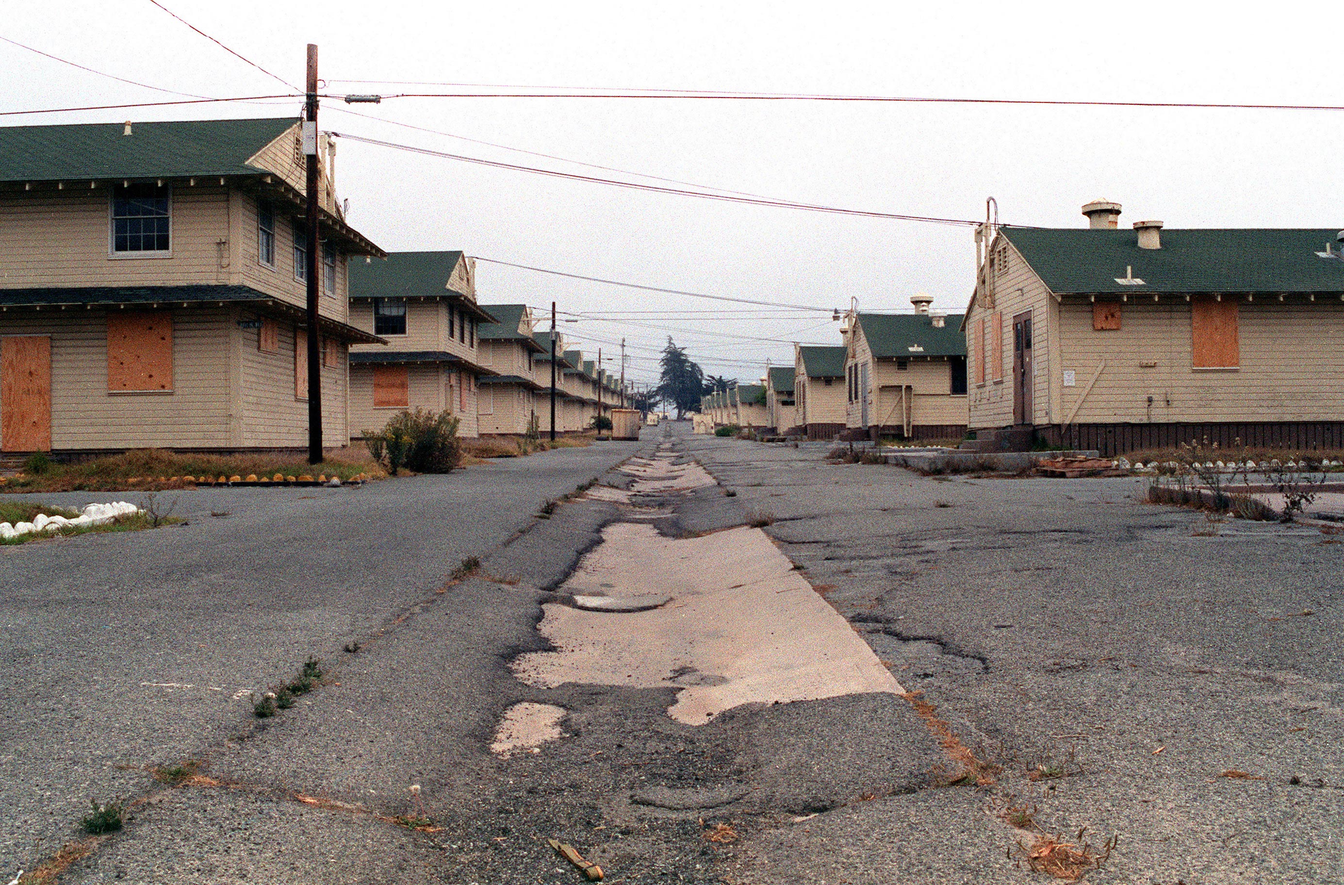 A photo of army barracks with windows and doors that are boarded up.