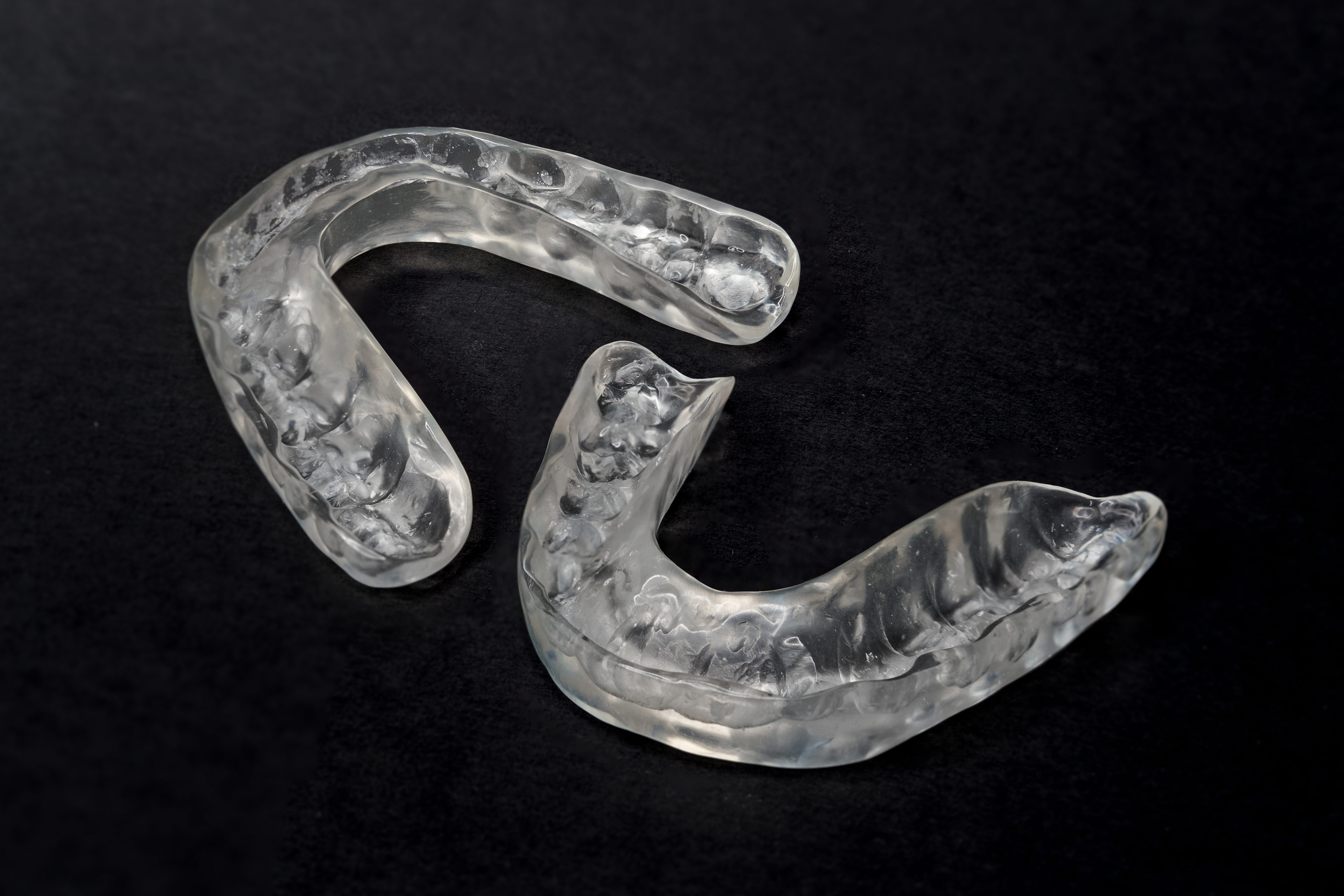 A photo of two dental splints on a black backdrop.