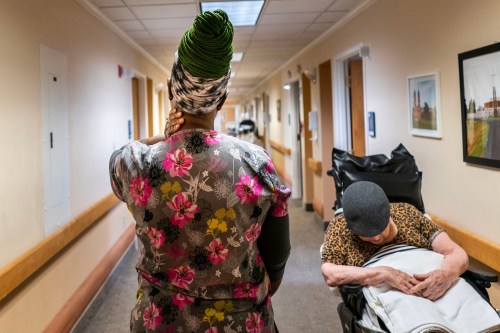 A woman walks down a corridor past a woman in a wheelchair