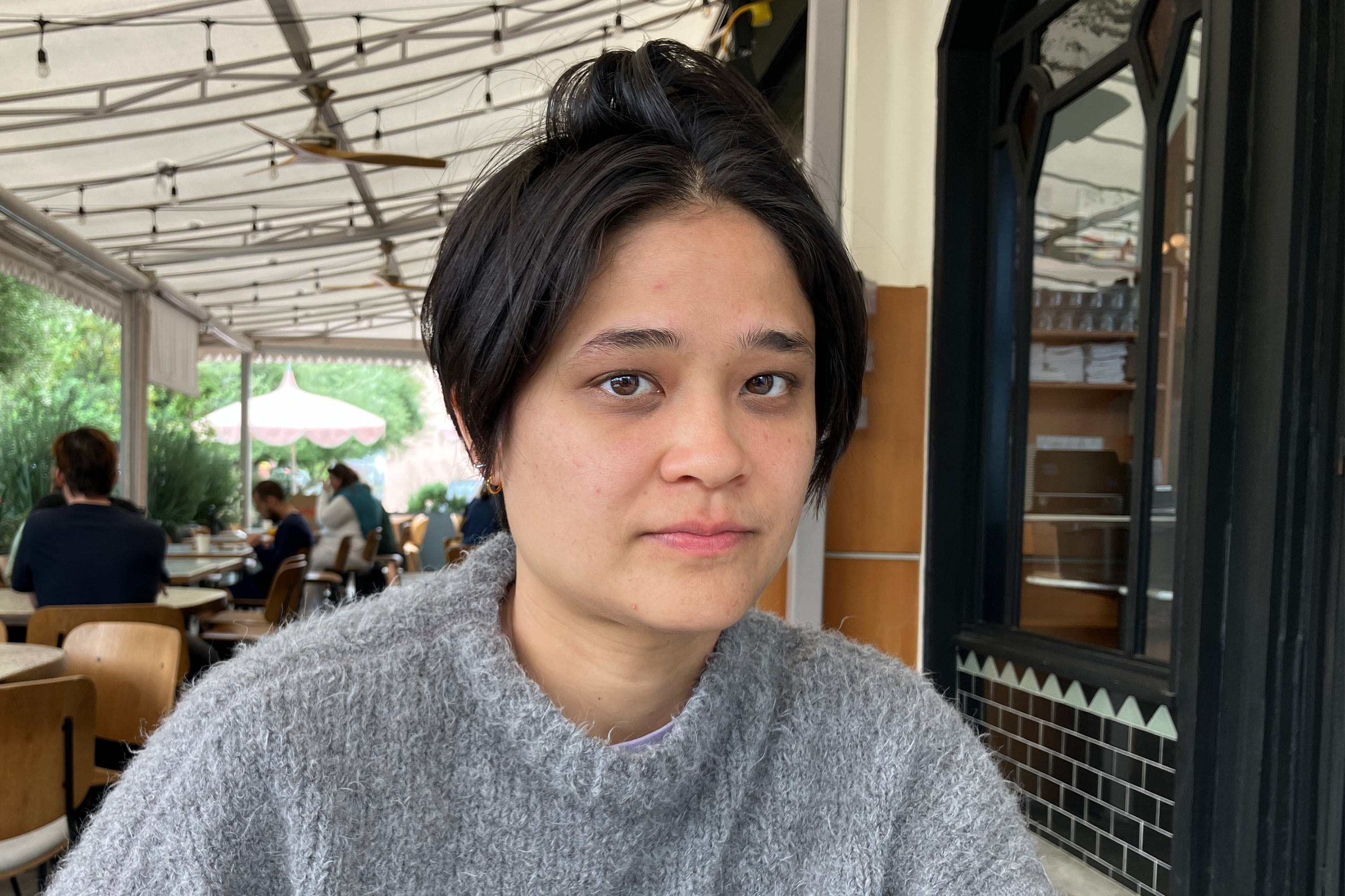 A photo of a woman sitting at a table outside.
