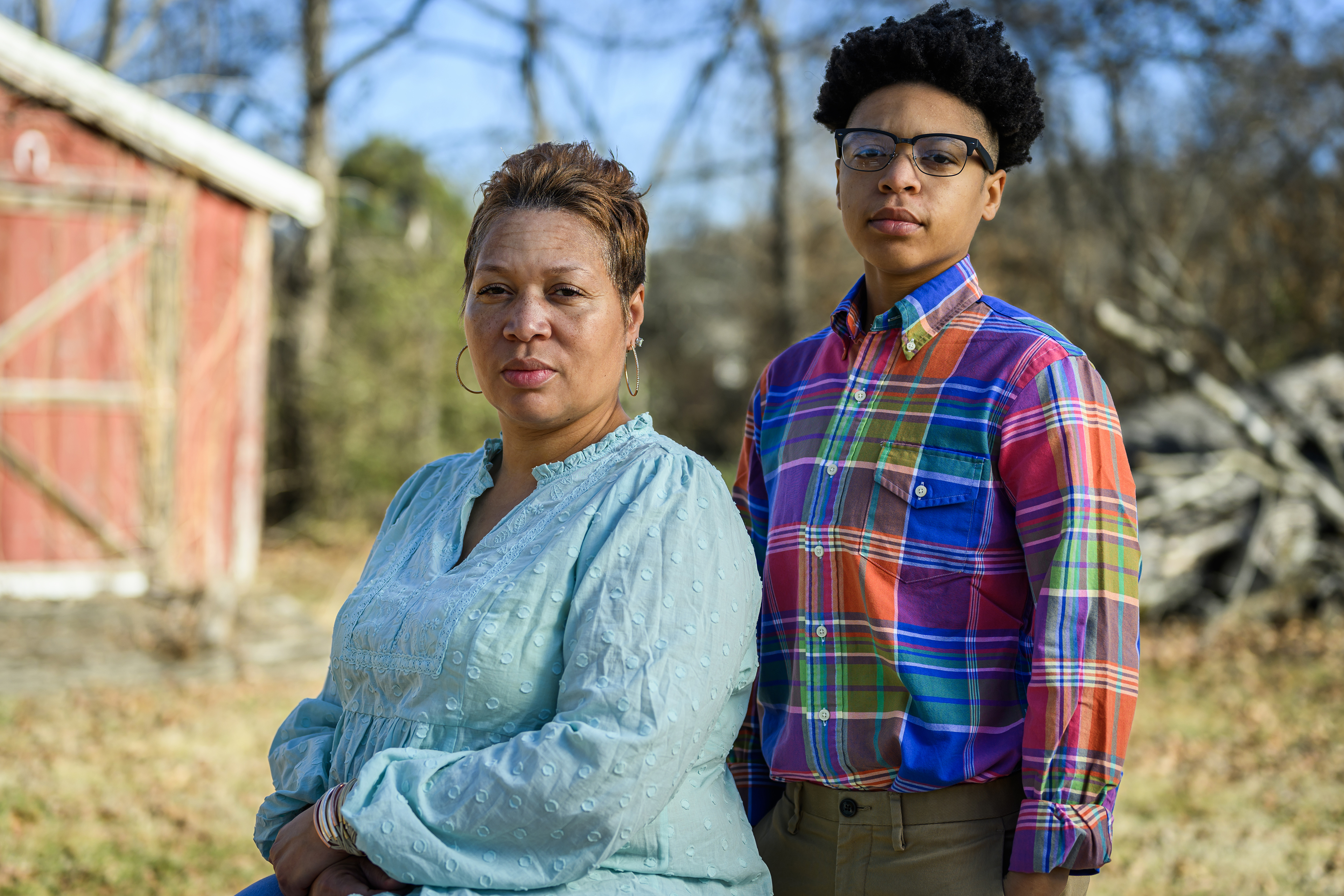 DiJuana Davis is sitting outside on a sunny day. Her child, Treasure Woodard, stands beside her.