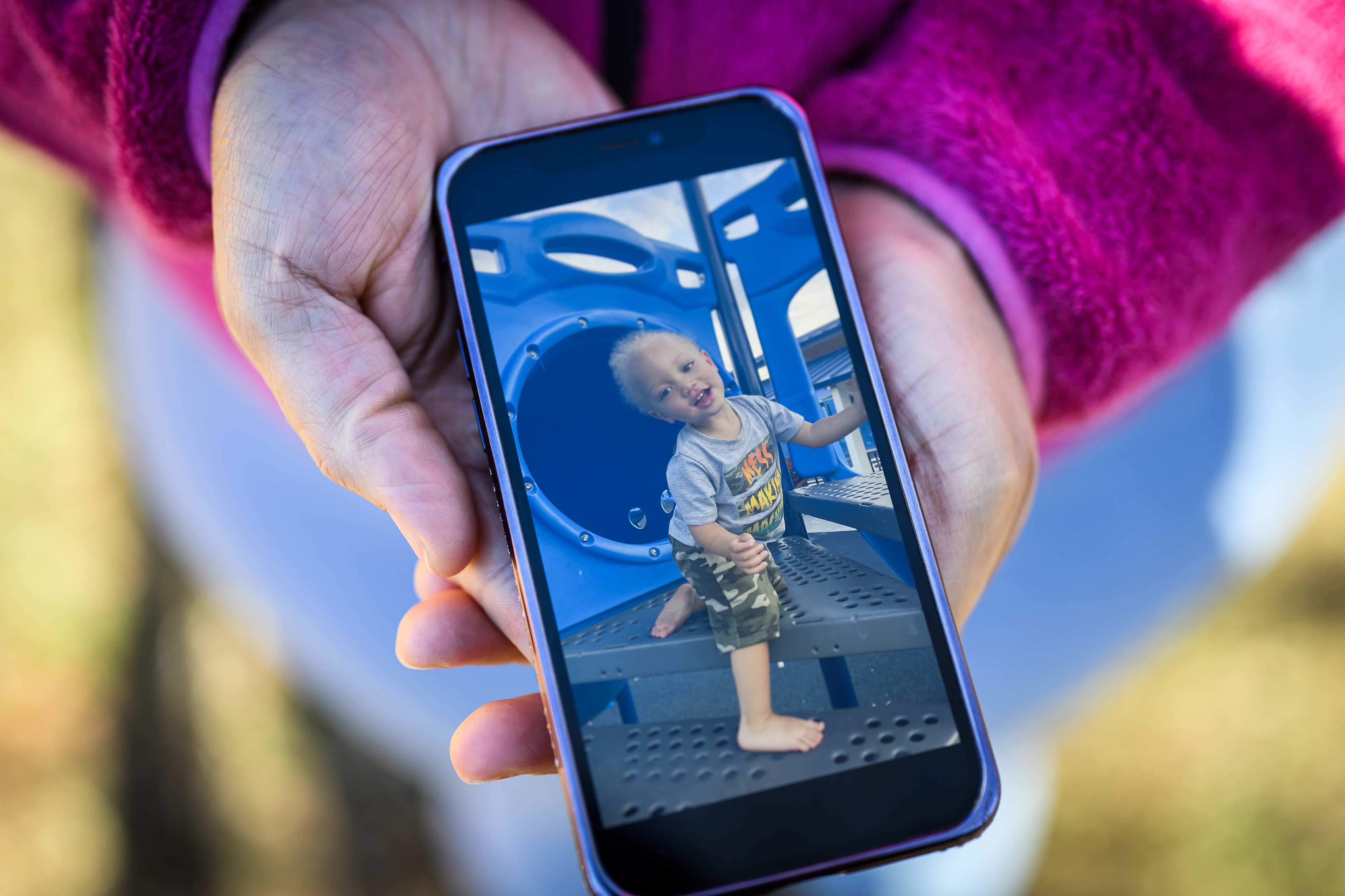 DiJuana Davis holds her smart phone with two hands, to show the photographer a photo of her youngest son, Vrai Davis-Smith.