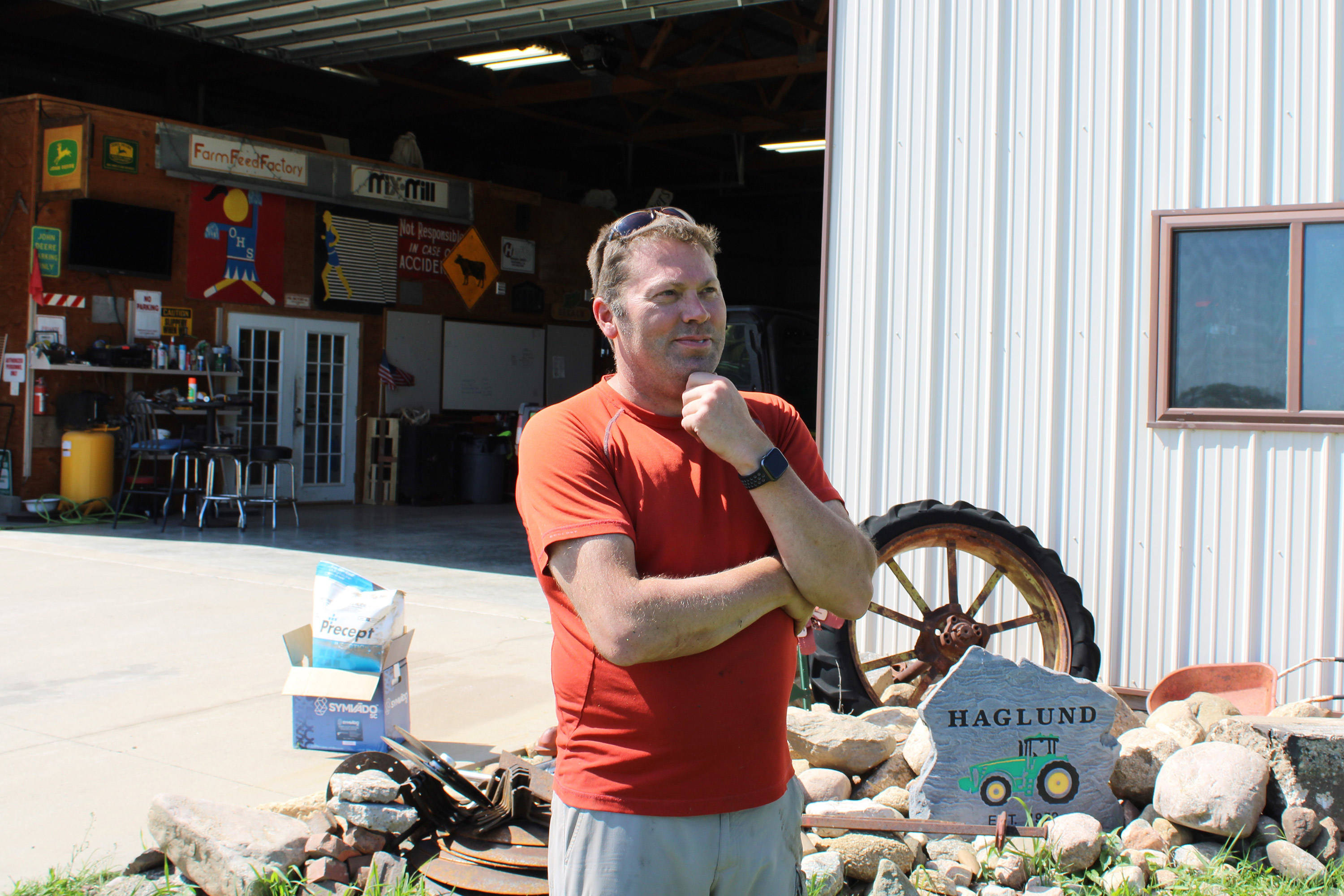 A photo of a man standing outside on his farm, looking out into the distance.