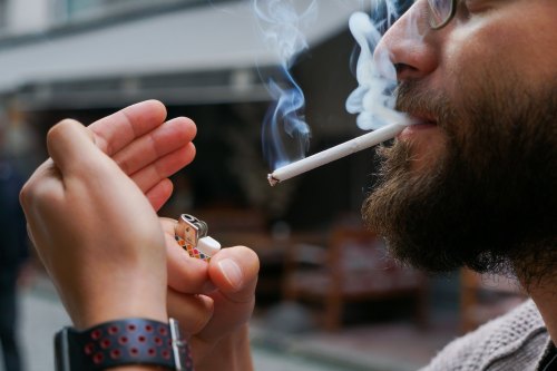 A photo of a man lighting a cigarette.